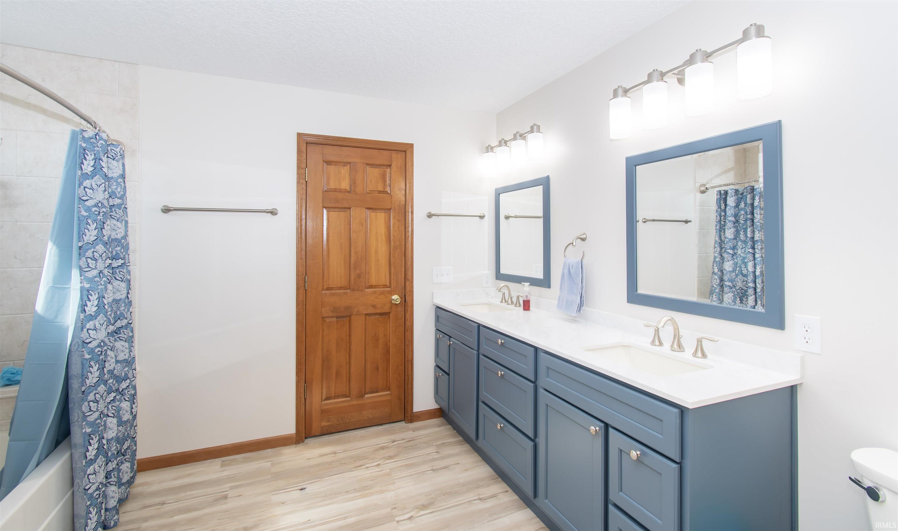 Bathroom featuring a double vanity with blue cabinetry, white countertops, and dual framed mirrors