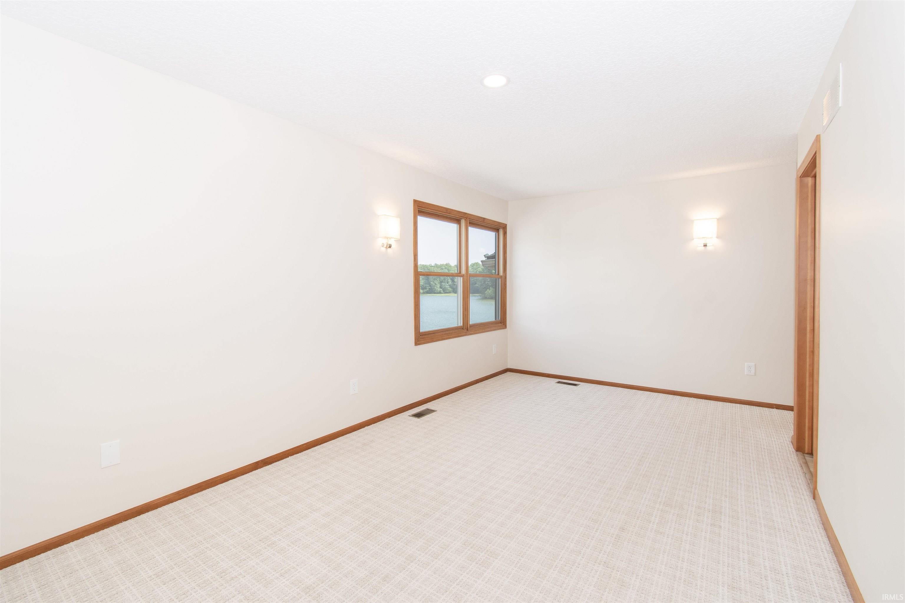 Carpeted room featuring a window with wood trim, offering a water scene