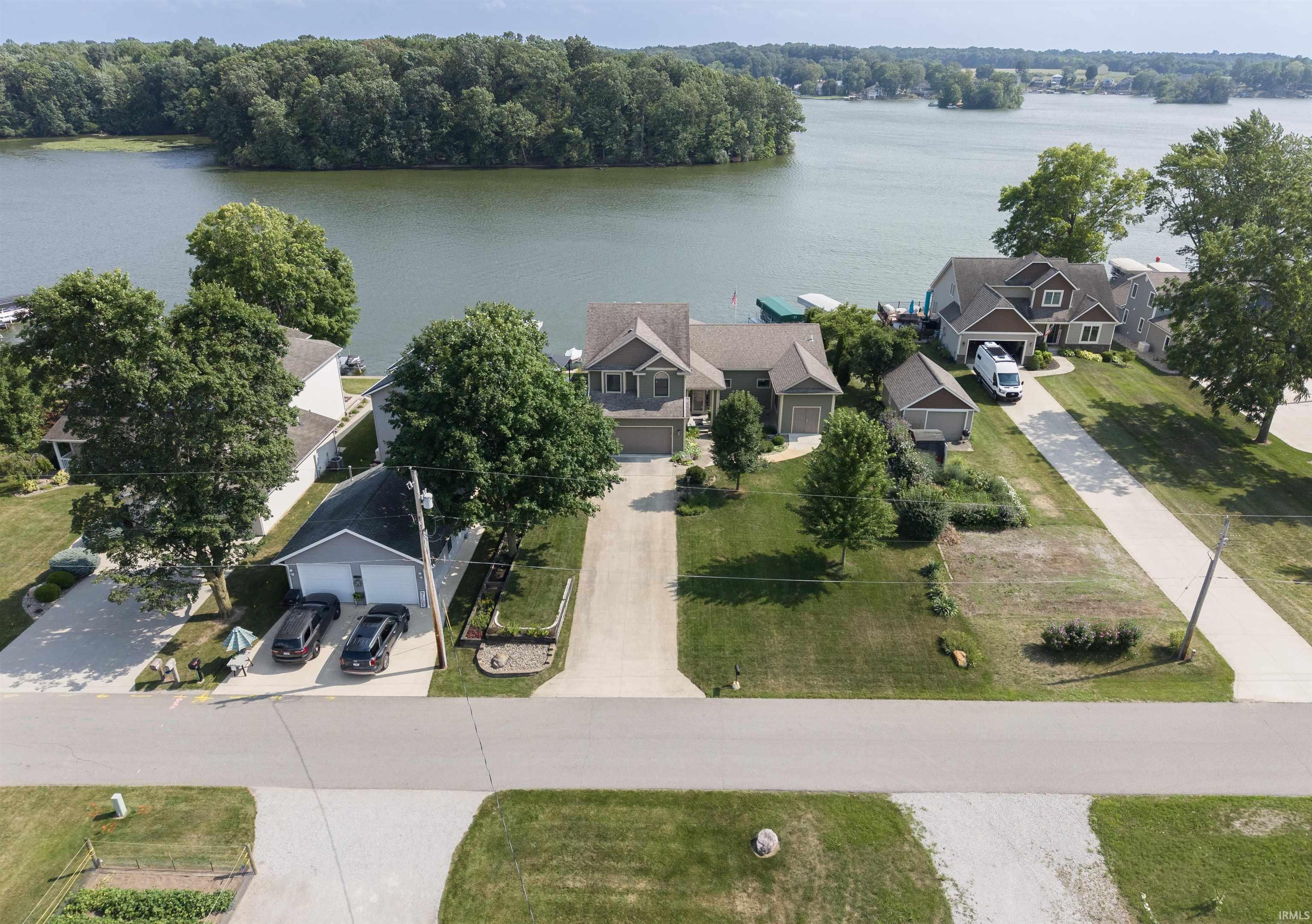 Waterfront property featuring a private boat dock, mature landscaping, and a multi-car driveway
