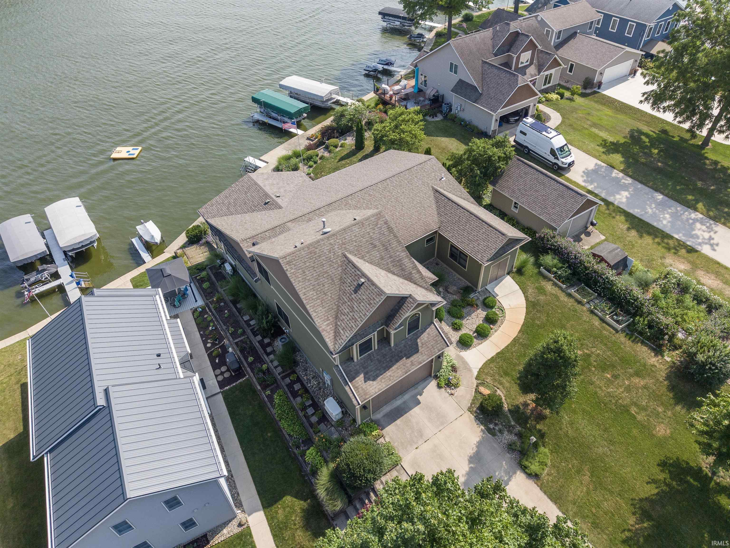 Waterfront property featuring multiple boat docks, a curving paved driveway, and a detached garage
