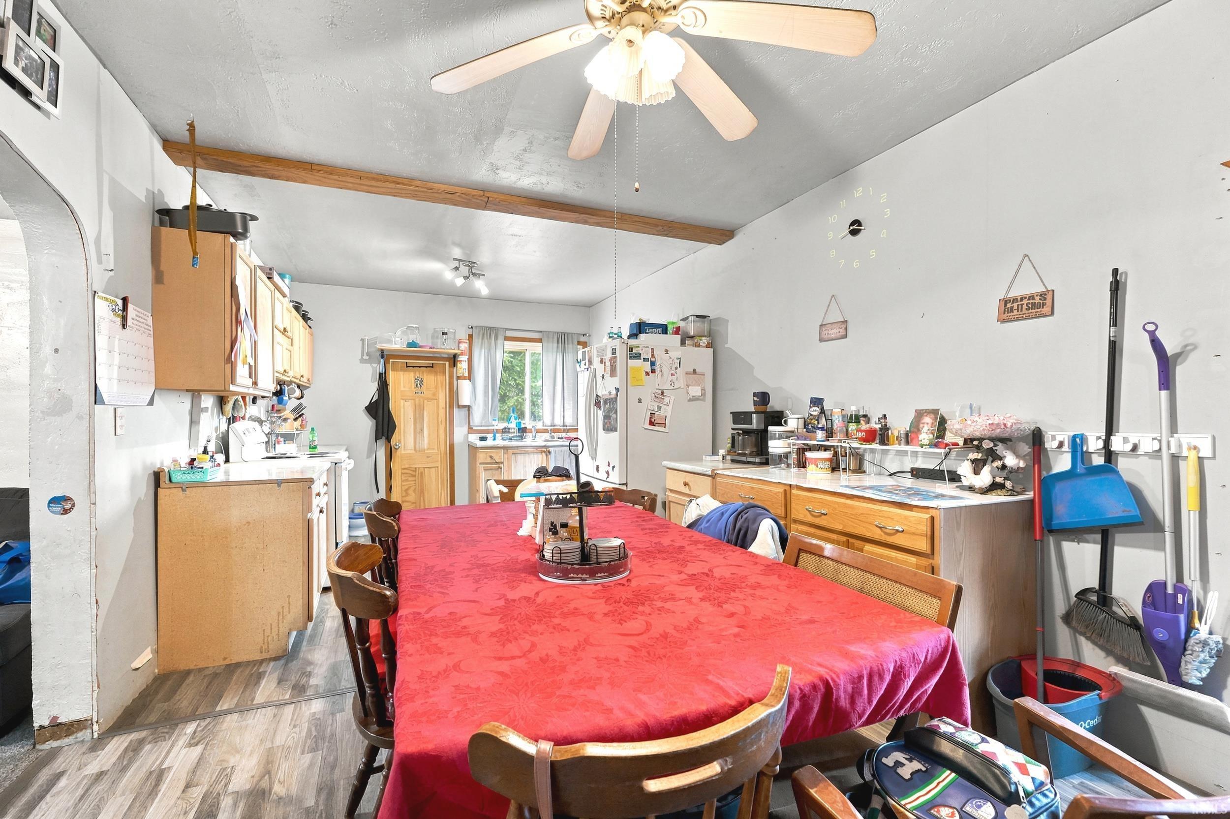 Spacious kitchen featuring wood-finish flooring, exposed ceiling beams, and a ceiling fan with integrated lighting
