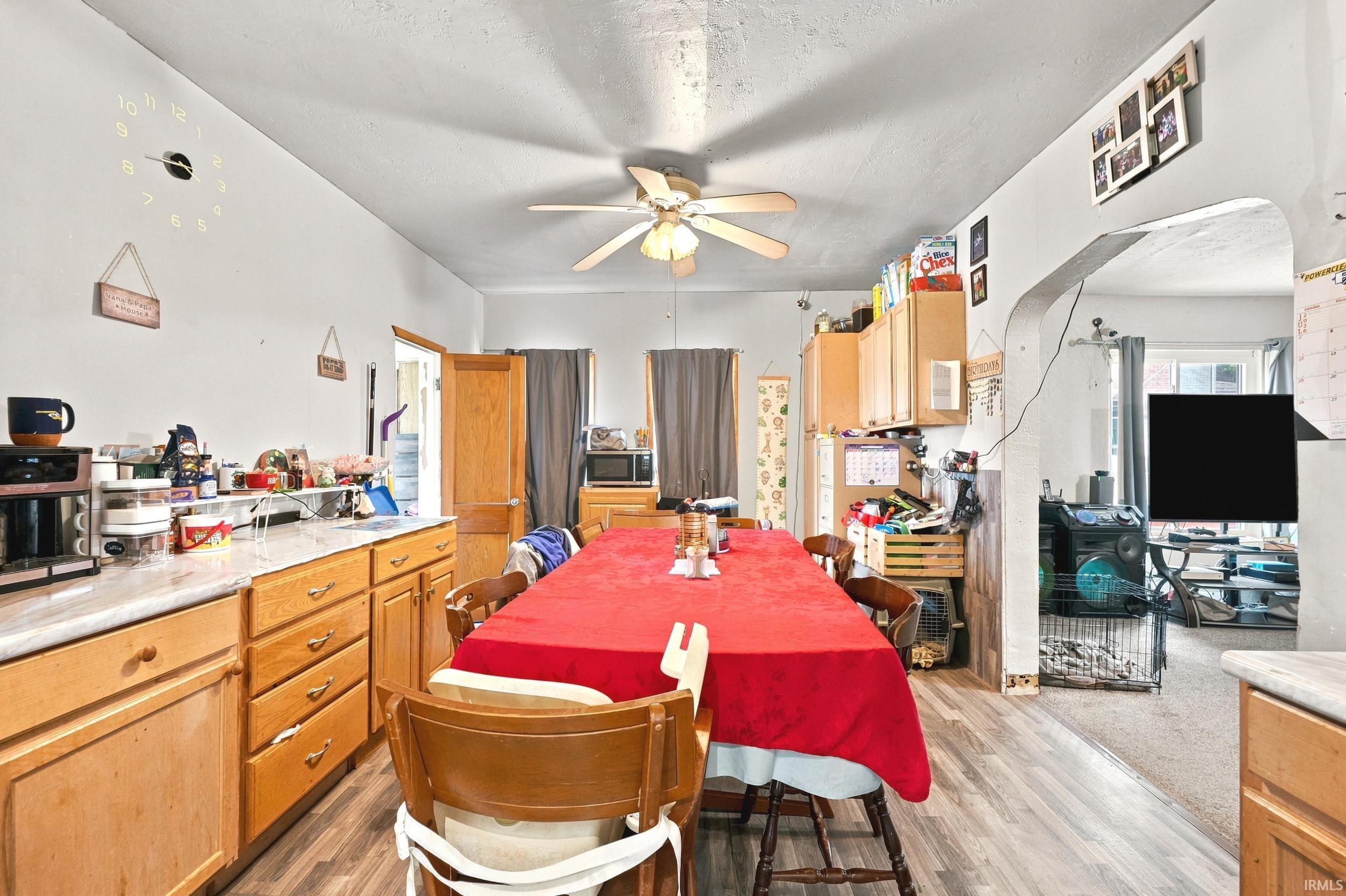 Kitchen area featuring wood-finish flooring, light wood cabinetry, light countertops, and a ceiling fan