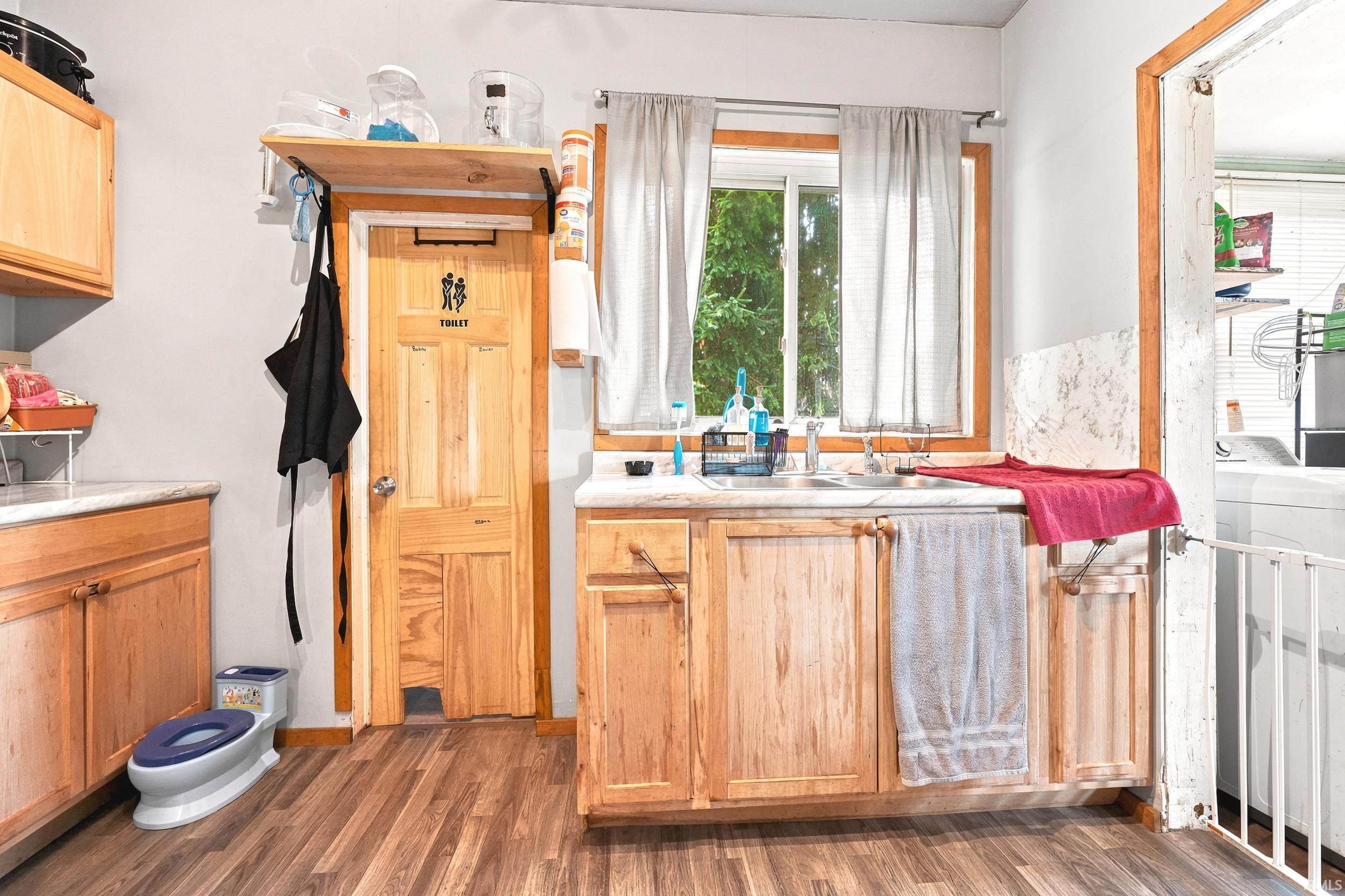 Kitchen area featuring wood-finish flooring, light-toned cabinetry, and solid surface countertops
