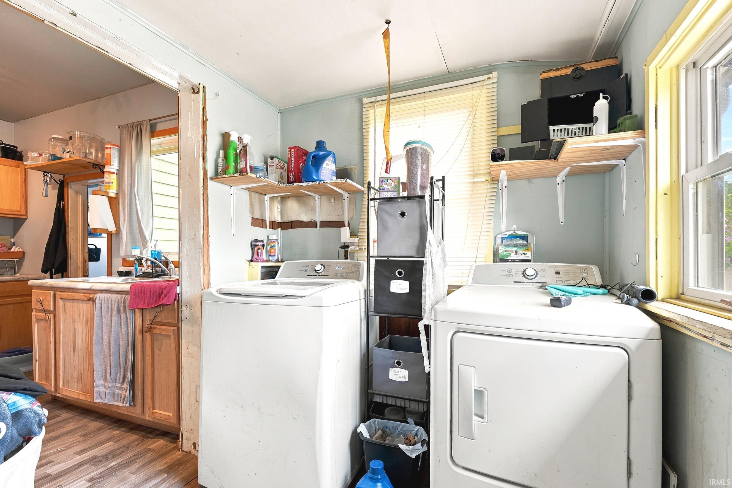 Dedicated laundry area featuring a washer and dryer, wood-finish flooring, and natural light from a window