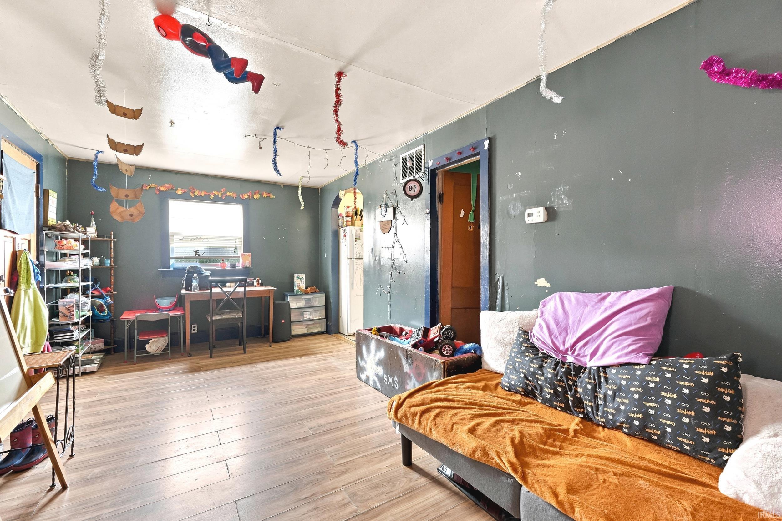 Hardwood-style flooring extends throughout this room, featuring a double window and a doorway with dark trim