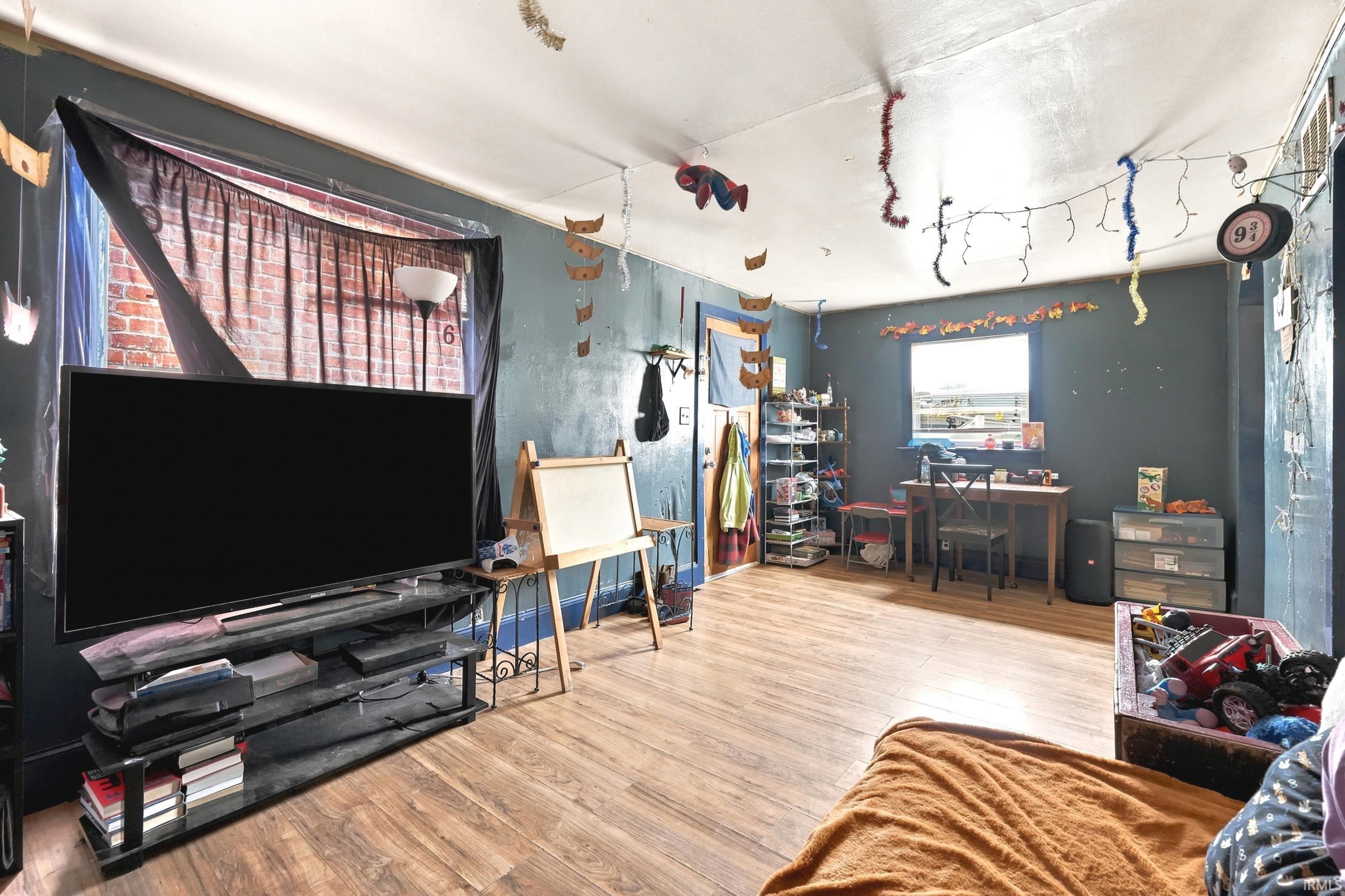 Interior space featuring wood-finish flooring, painted walls, and a window with a brick exterior visible