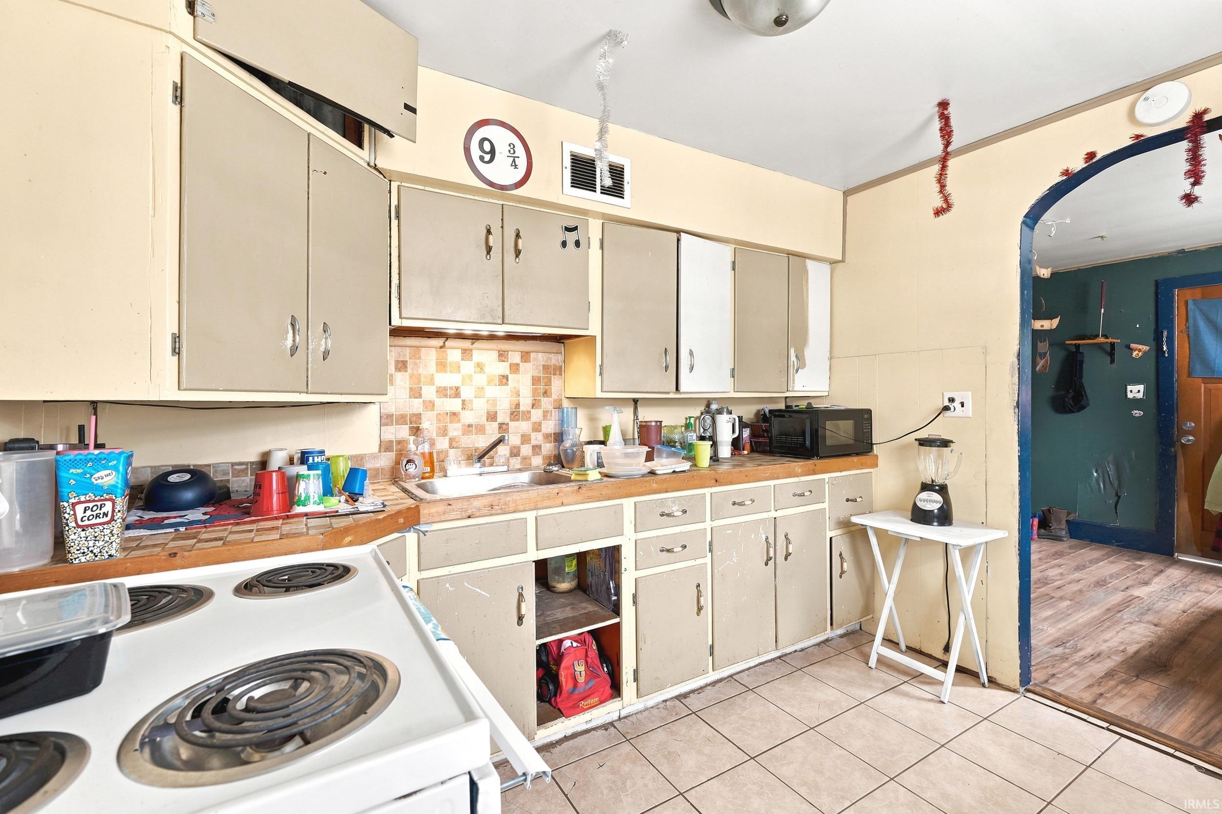 Kitchen featuring extensive cabinetry, tile backsplash, laminate countertops, a built-in sink, and tile flooring