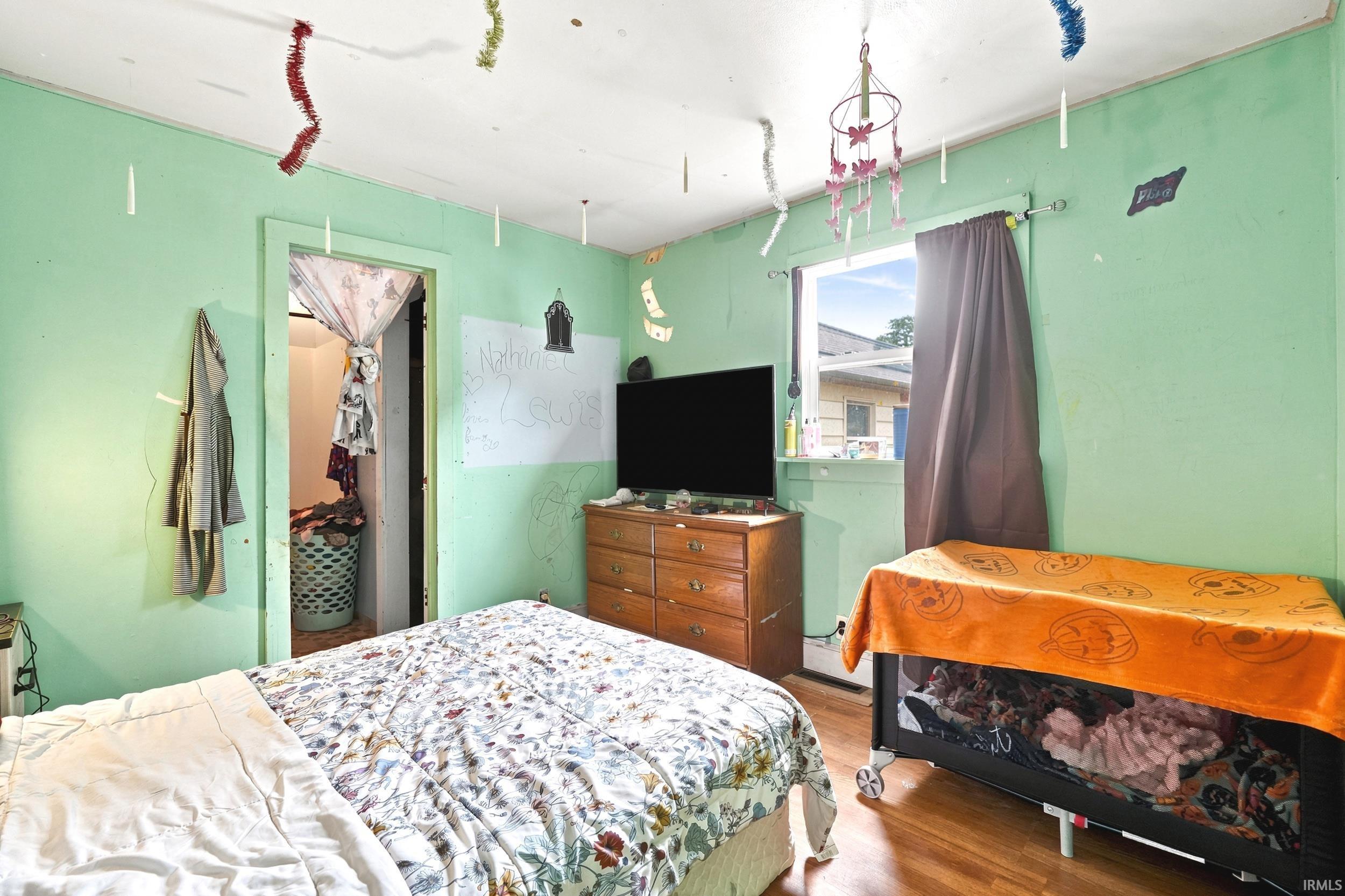 Hardwood-style flooring and a single window with dark curtains define this room