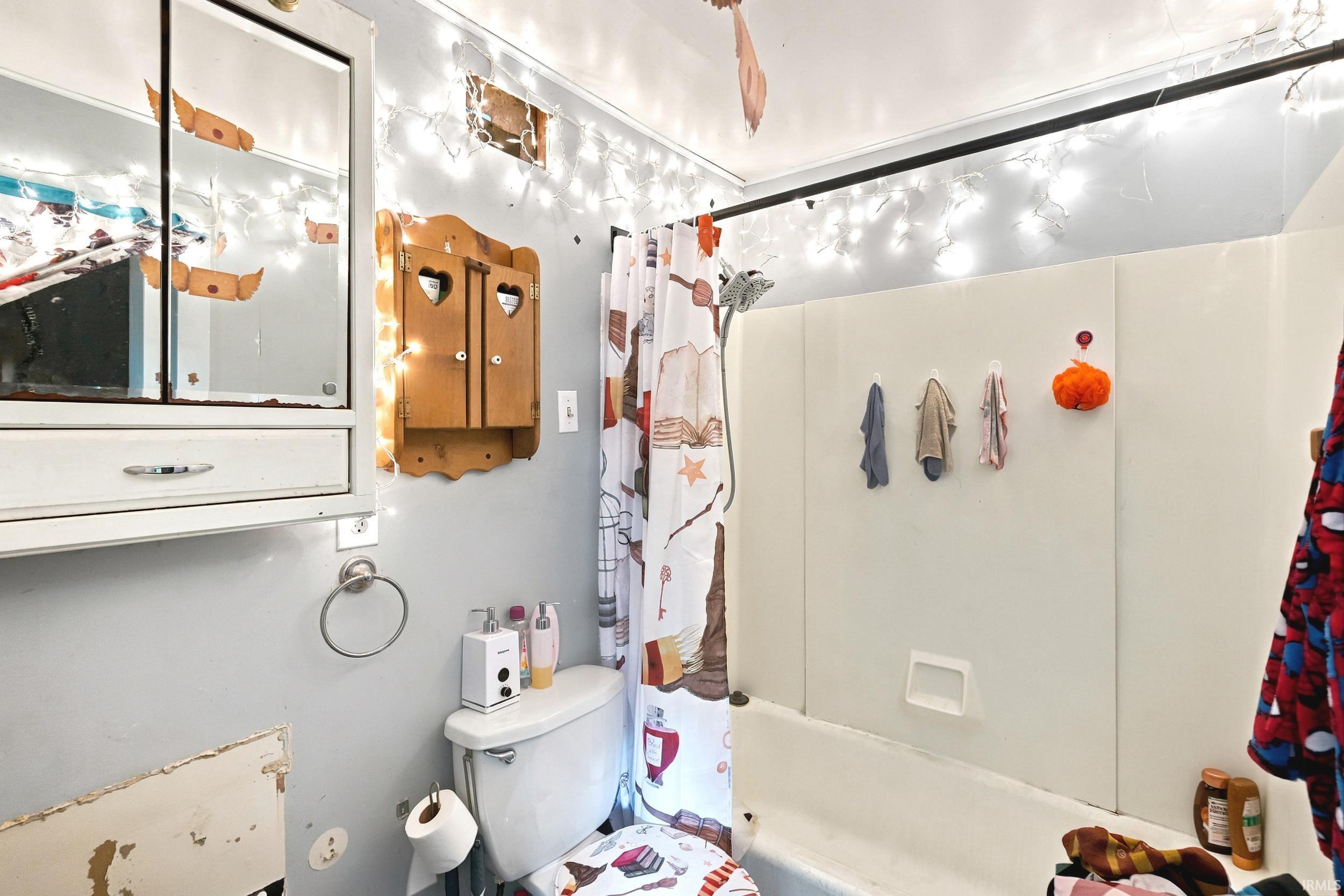White porcelain toilet with an attached paper holder, accompanied by a wall-mounted wooden cabinet featuring heart cutouts