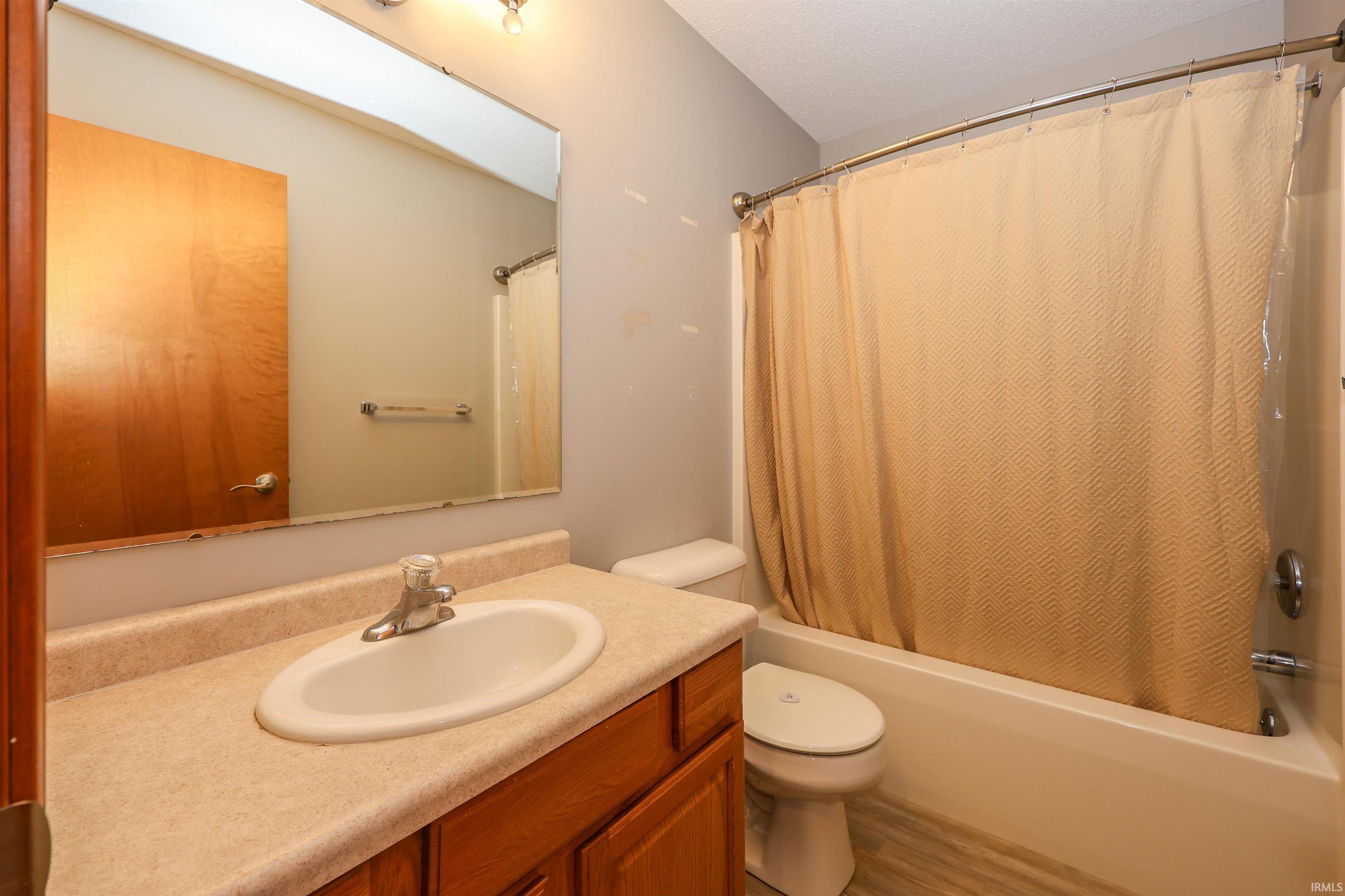 Bathroom featuring a vanity with a laminate countertop, integrated sink, and wood cabinetry