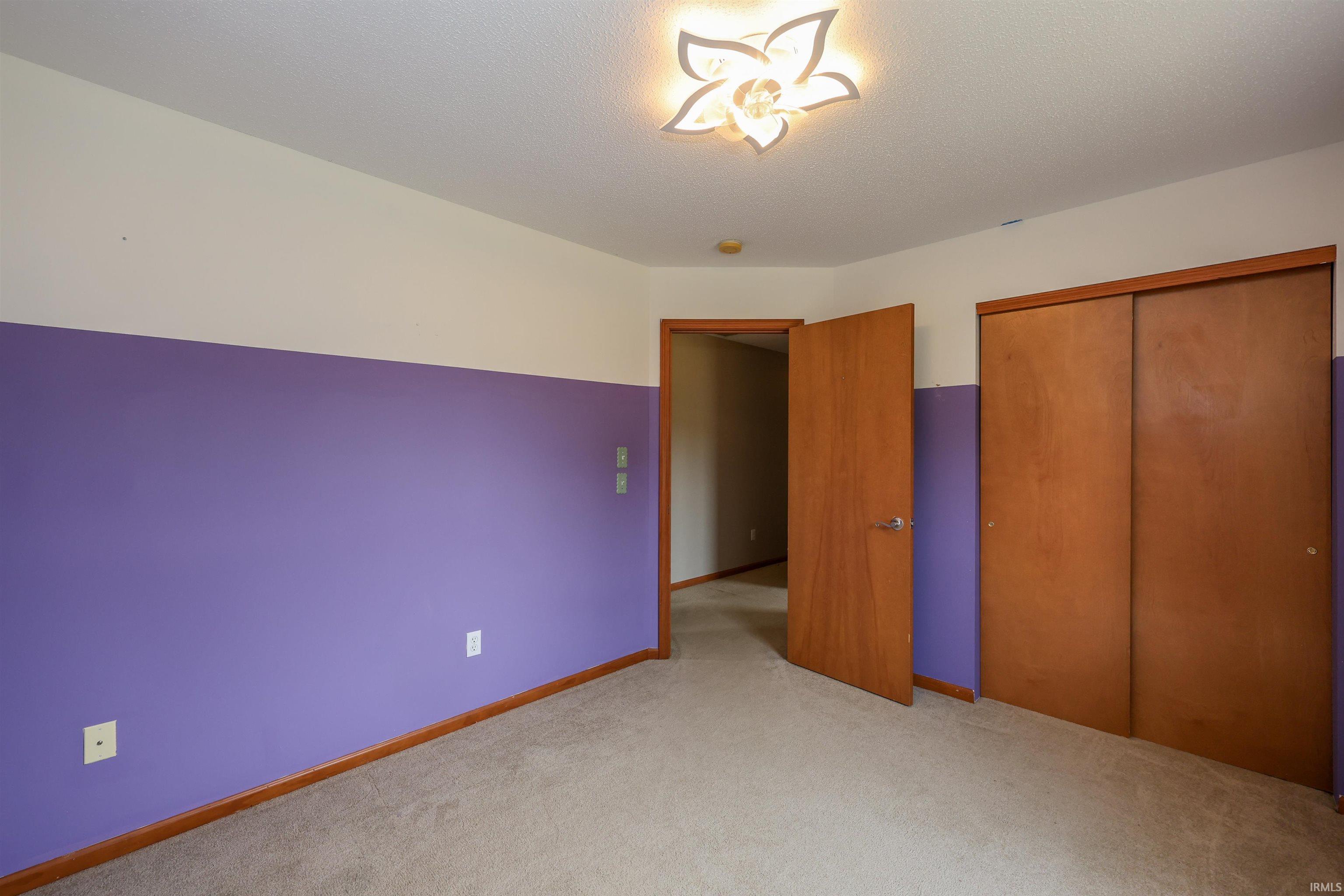 Carpeted interior room featuring a decorative ceiling light fixture, wood-finish doors, and baseboards