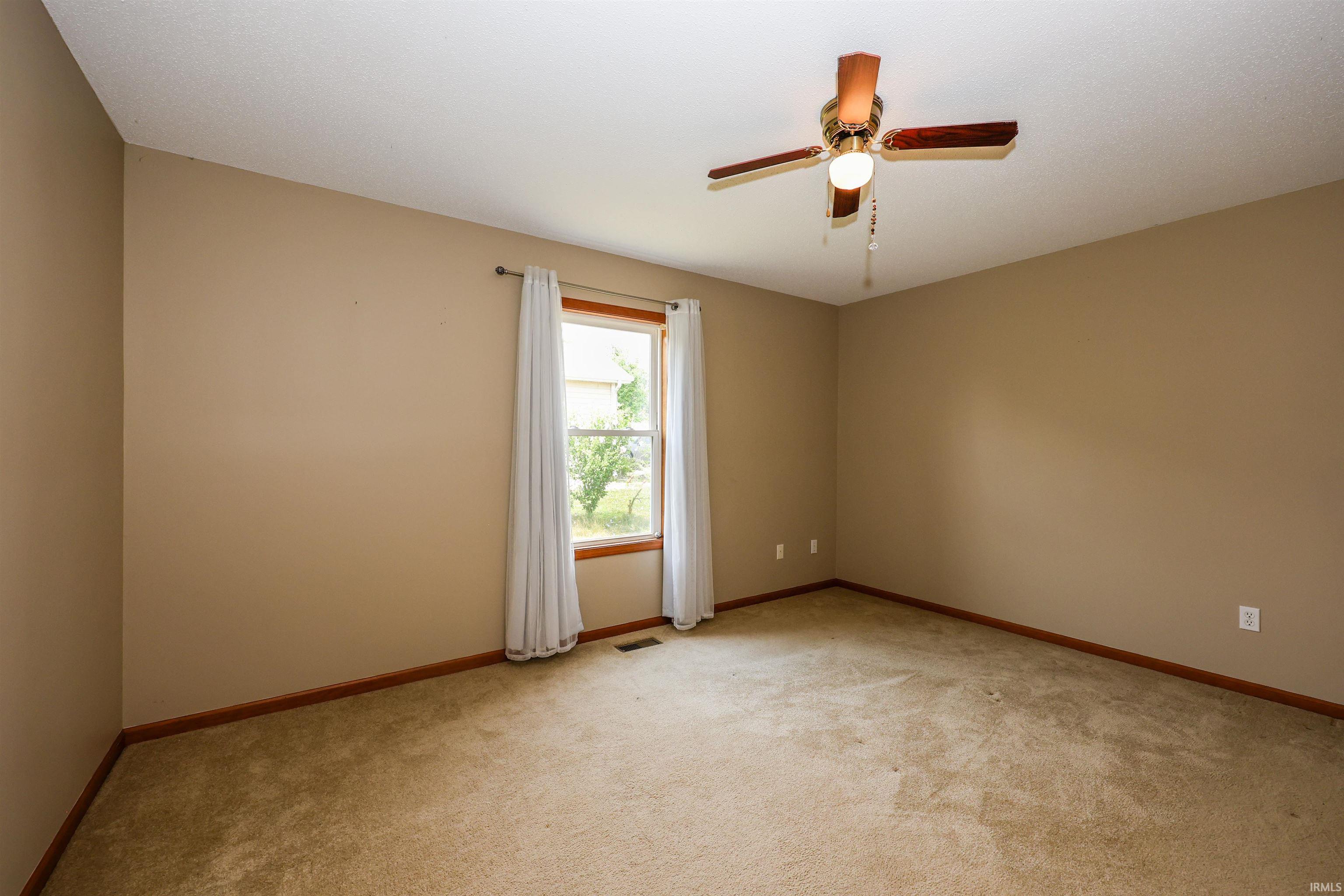Carpeted room with a ceiling fan light fixture