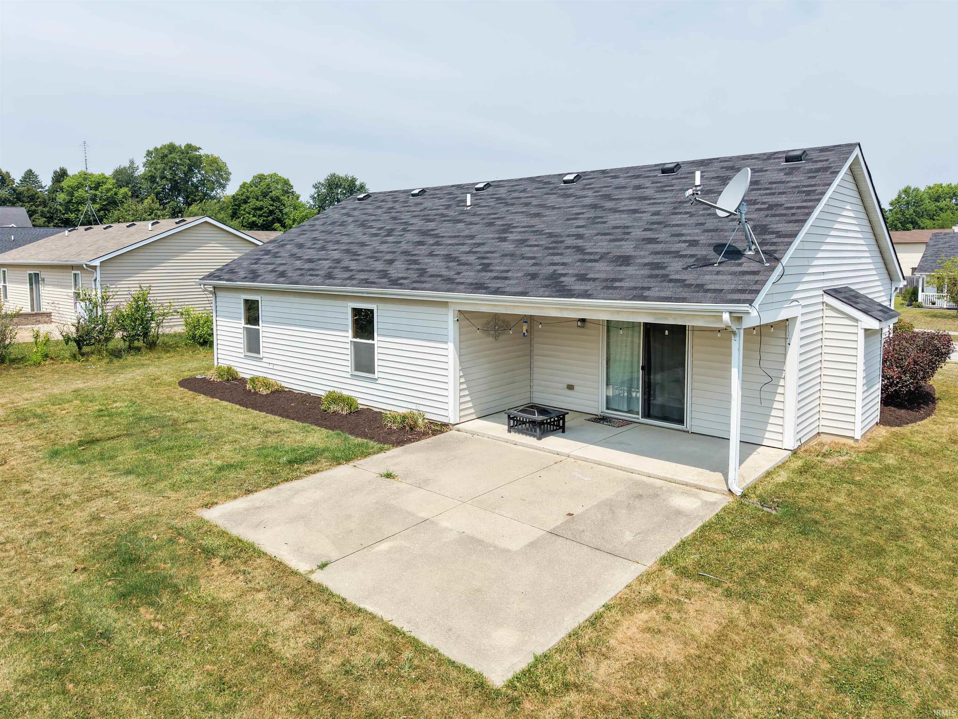 Rear exterior featuring a covered concrete patio, sliding glass door, and white siding