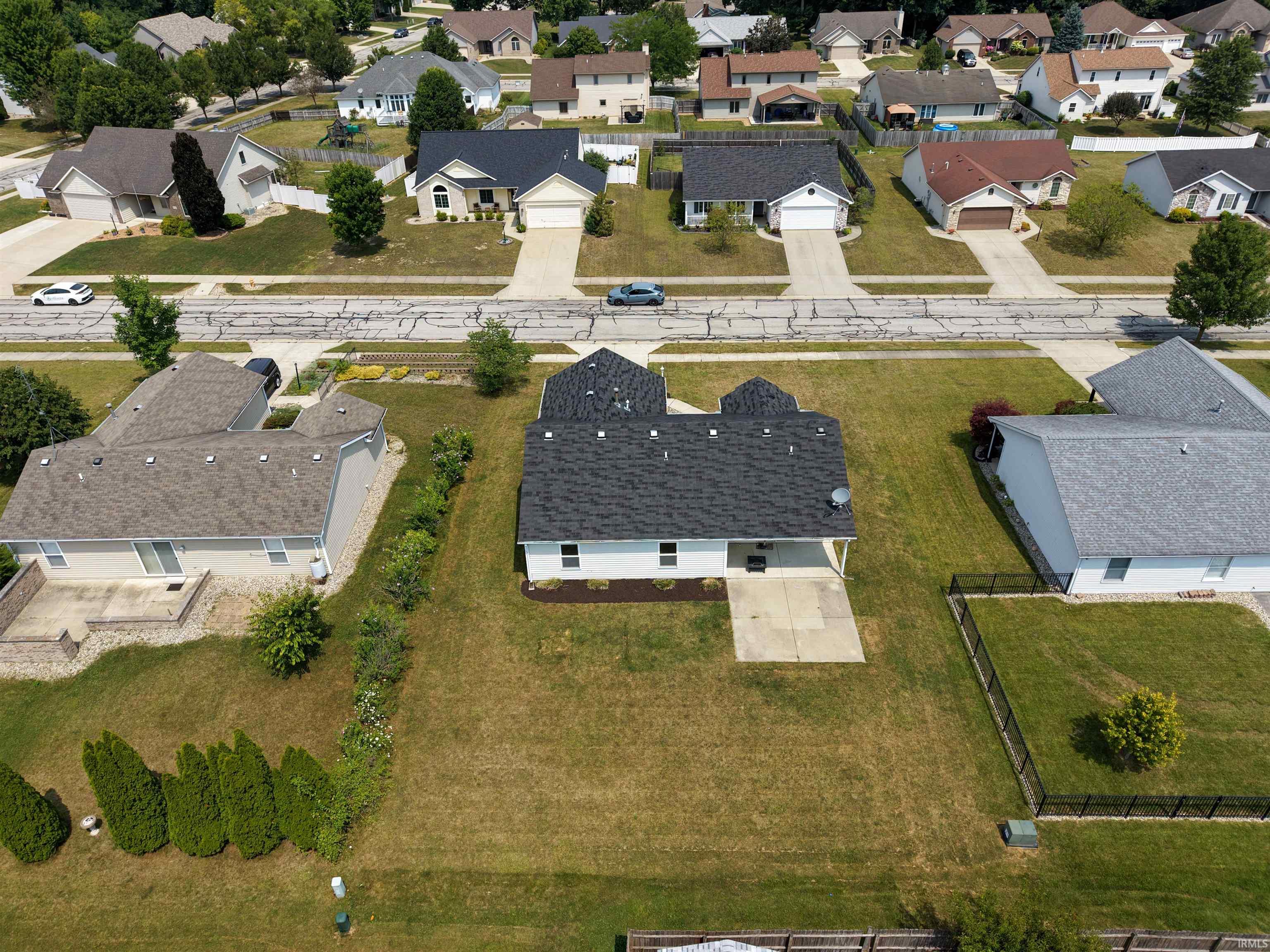 Aerial perspective showcasing a single-story residence with a dark shingle roof and white siding