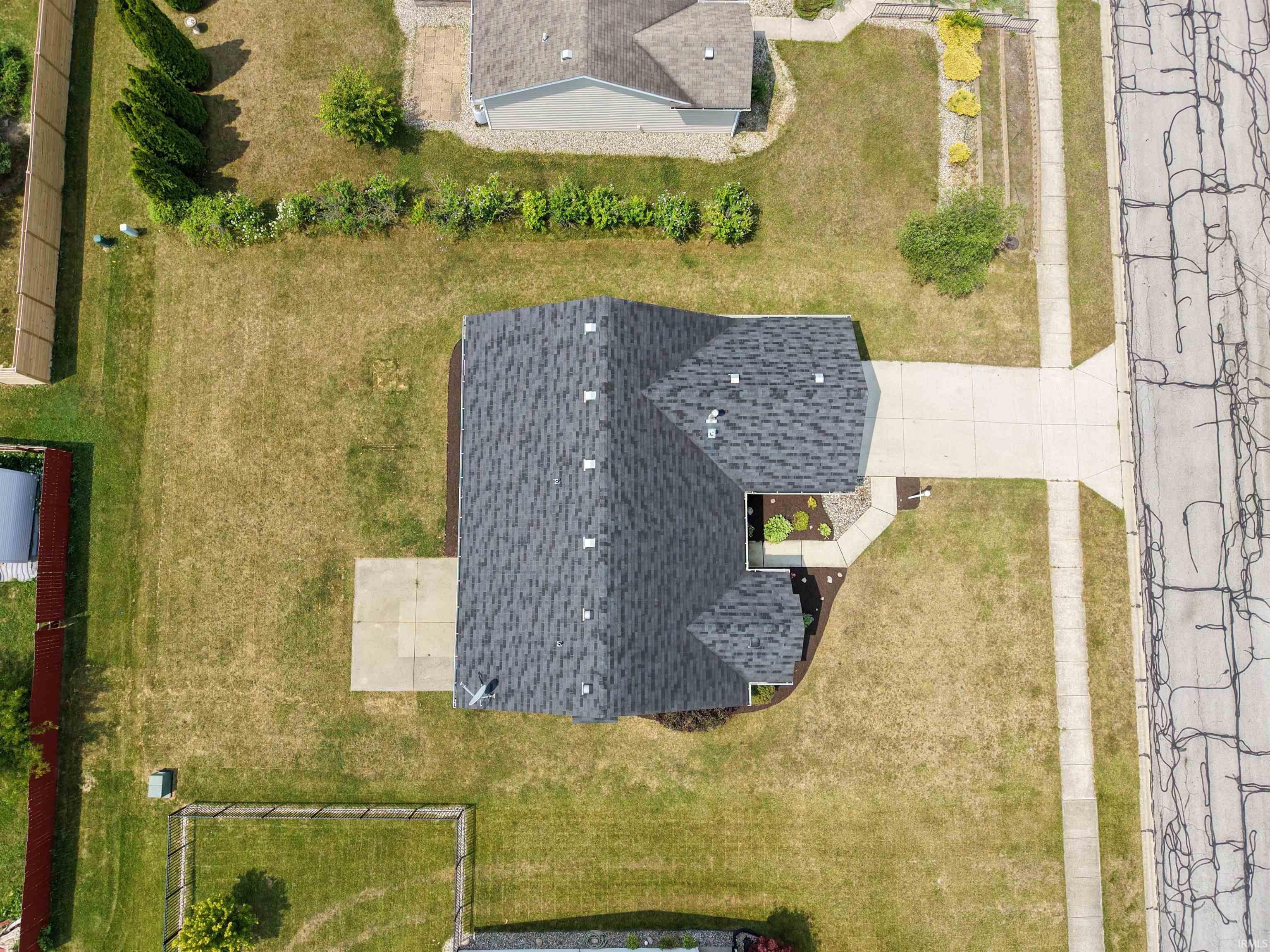 Property featuring a gray shingle roof, concrete driveway, front walkway, and a landscaped garden bed