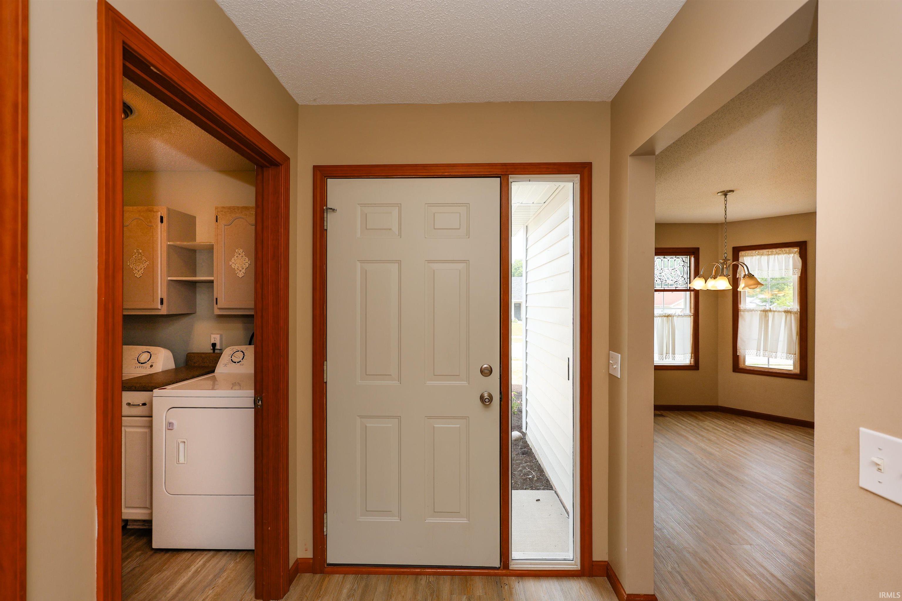 Inviting entryway featuring a paneled door with a sidelight, wood-finish flooring, and warm wall tones