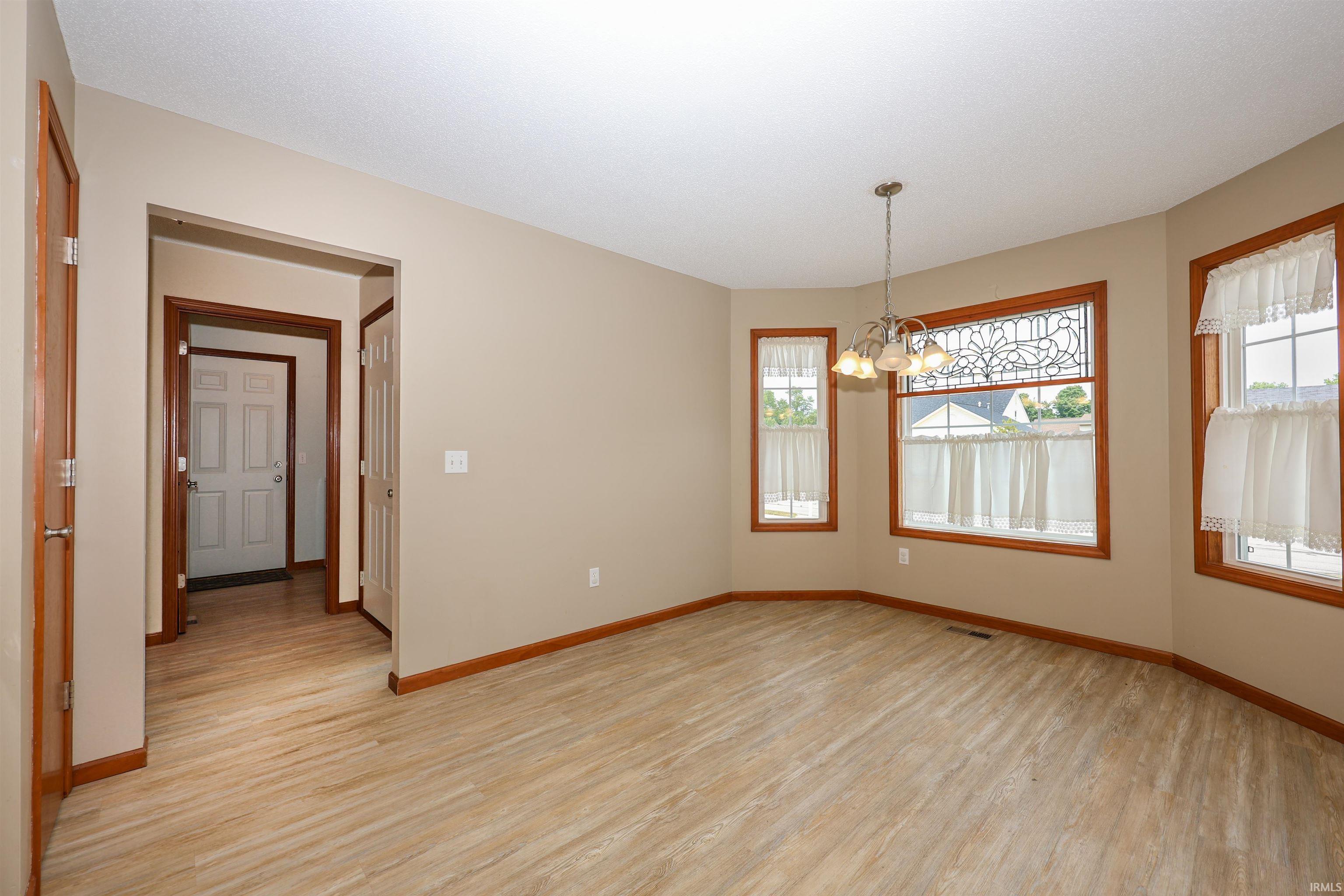 Bay window with decorative transom, wood-finish flooring, recessed lighting, and a multi-light chandelier