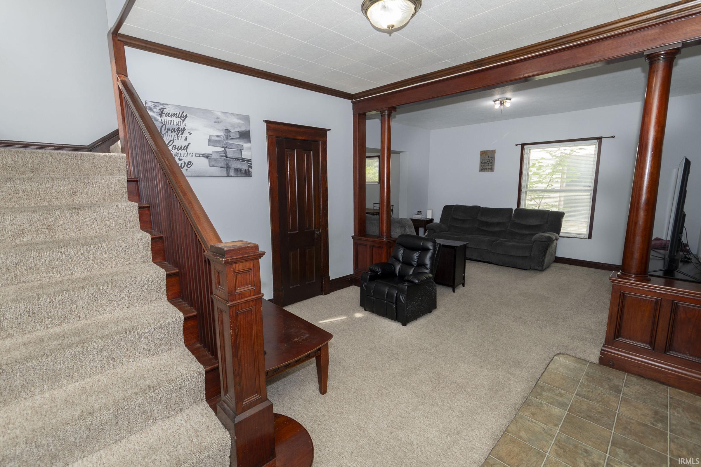 Entryway and living area featuring a traditional wood staircase with carpeted treads