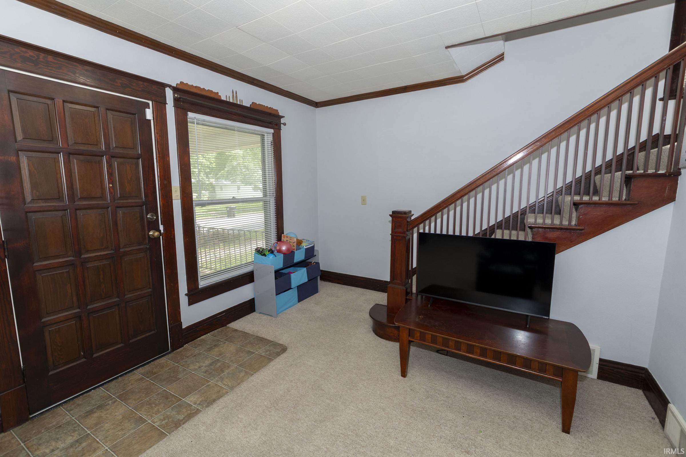Entryway featuring a paneled wood door, a single-pane window with blinds, and rich wood trim