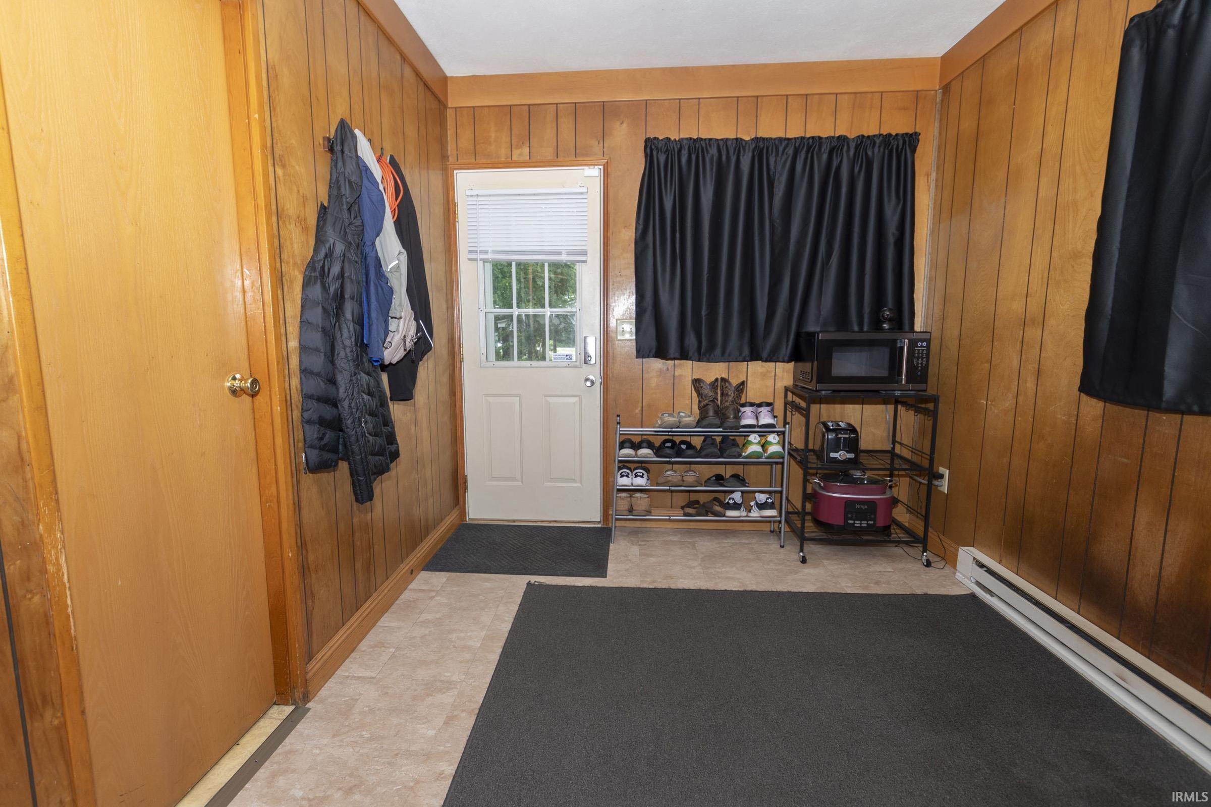 Room featuring light wood paneling, a light-colored door with a brass doorknob, and a white exterior door with window panes