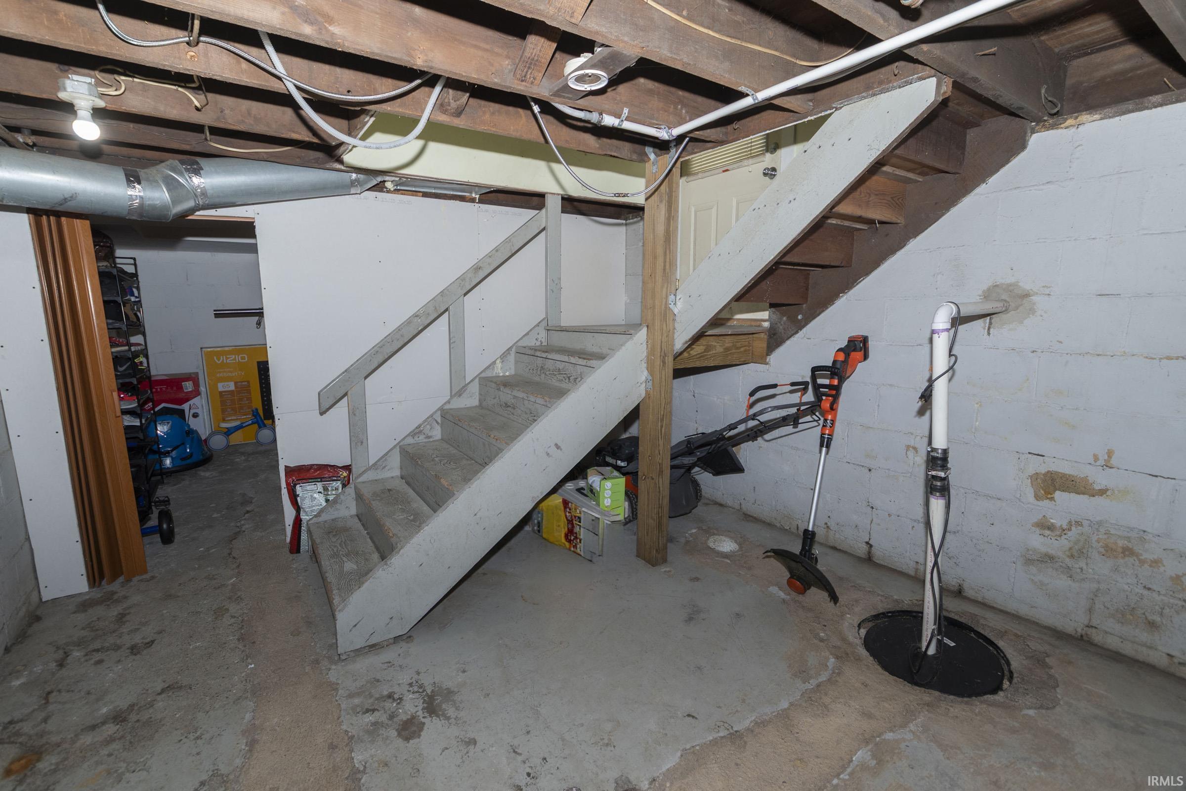 Concrete staircase with painted treads, exposed wood joists, and a concrete floor