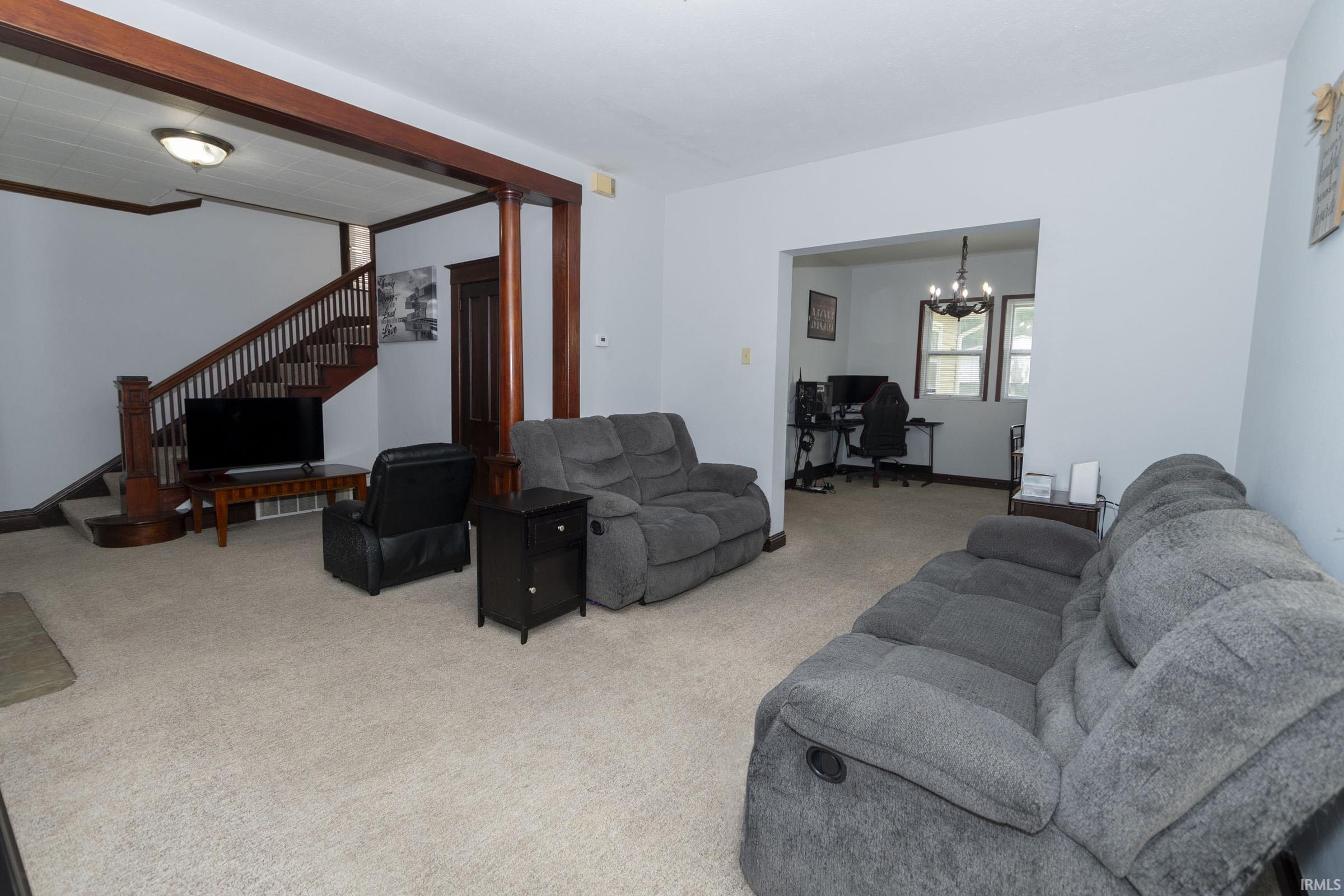 Spacious living area featuring light-toned carpeting and light gray walls
