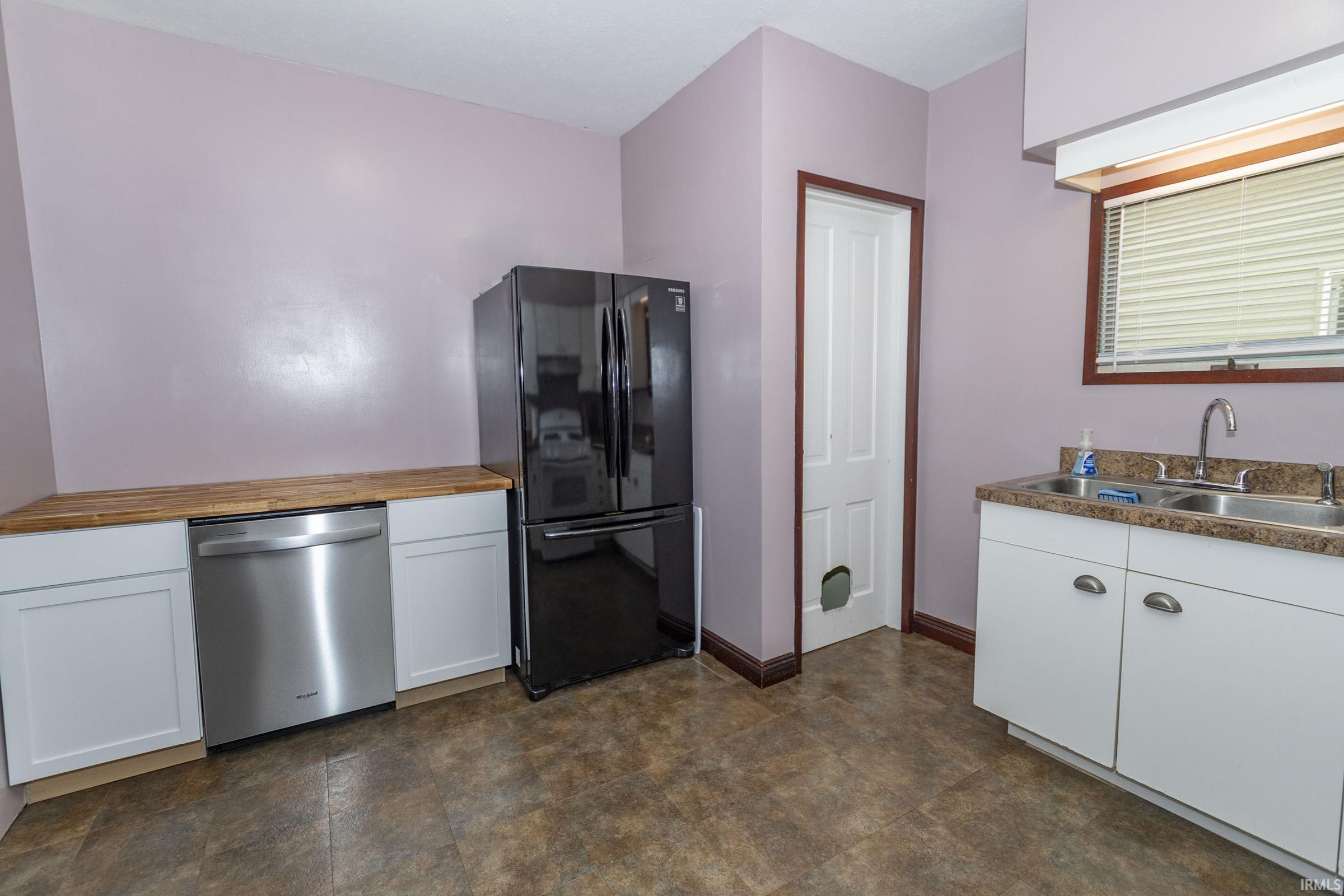 Kitchen featuring white shaker-style cabinetry and wood-finish countertops
