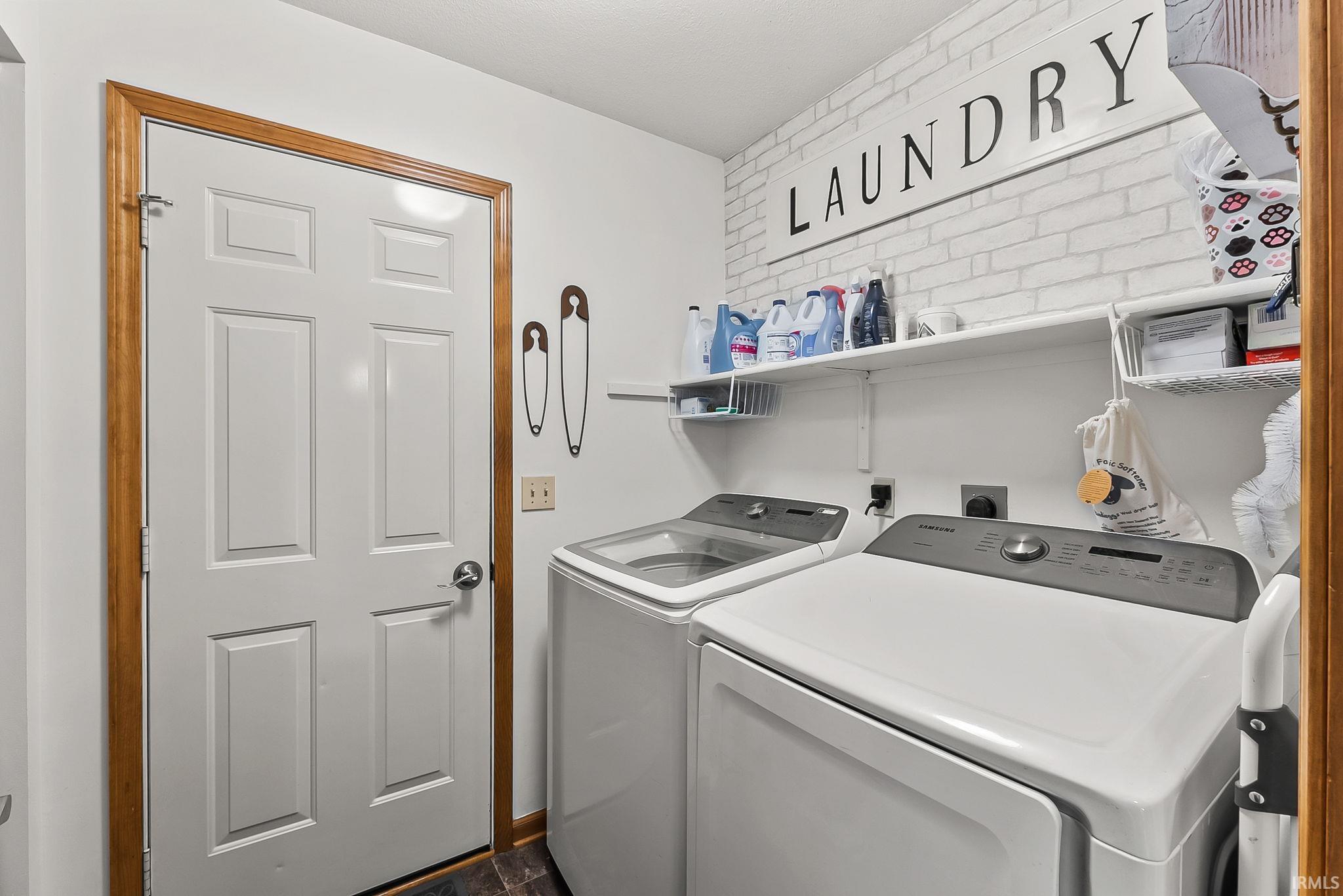 Dedicated laundry space featuring a white paneled door with wood-finish trim, white shelving, and a patterned accent wall