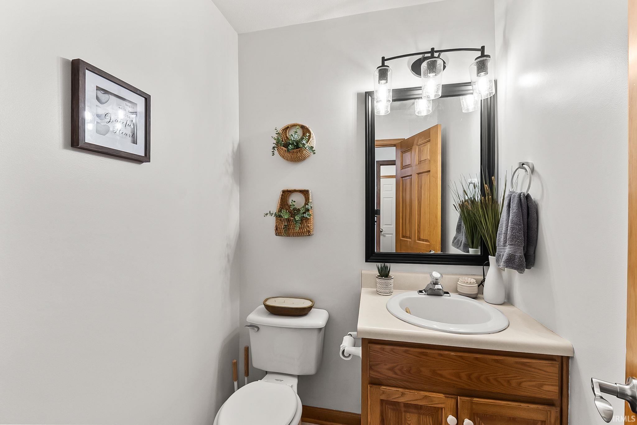 Powder room featuring a corner vanity with a wood-finish cabinet and an integrated sink