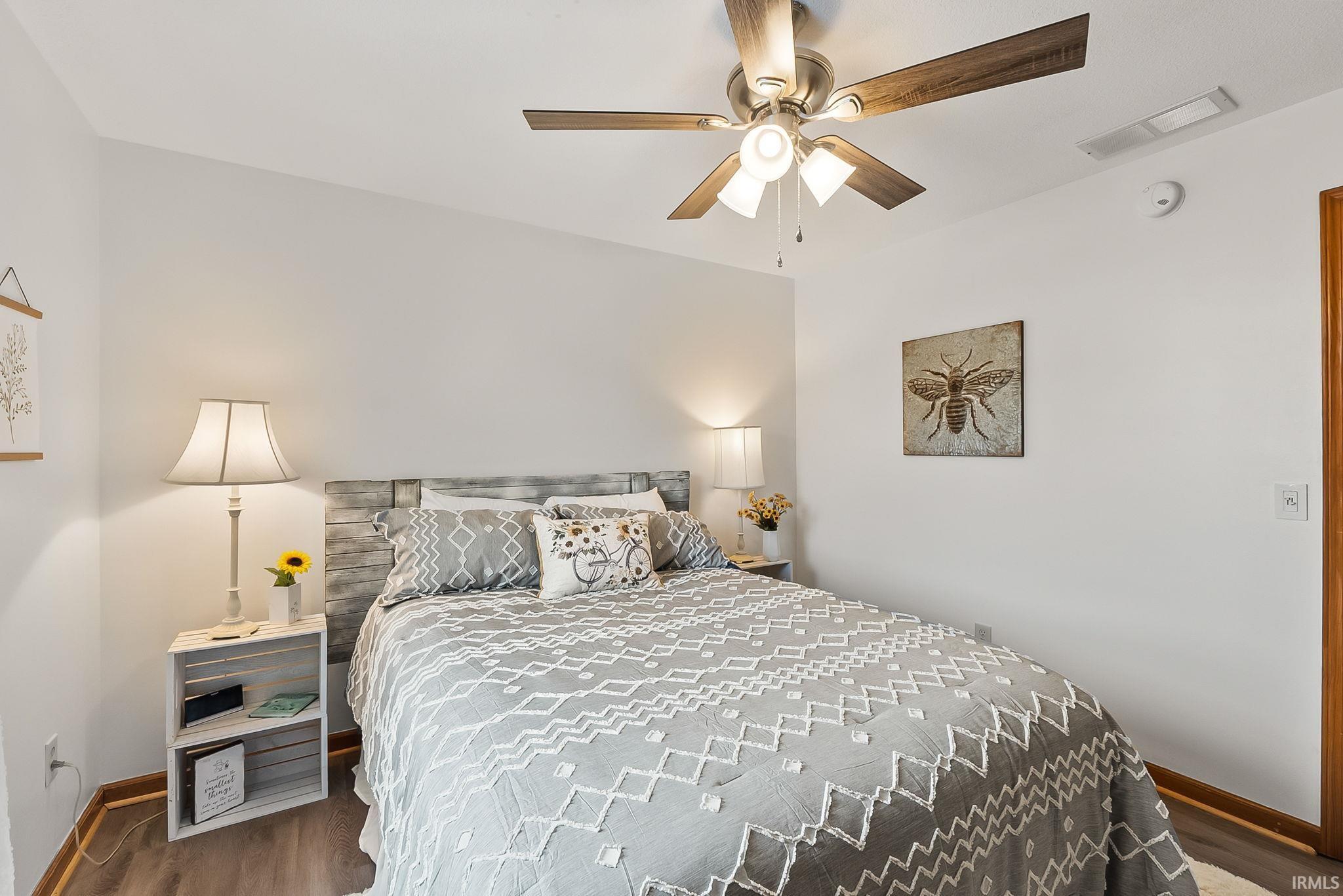 Bedroom featuring wood-finish flooring, a ceiling fan with integrated lighting, and a neutral color palette