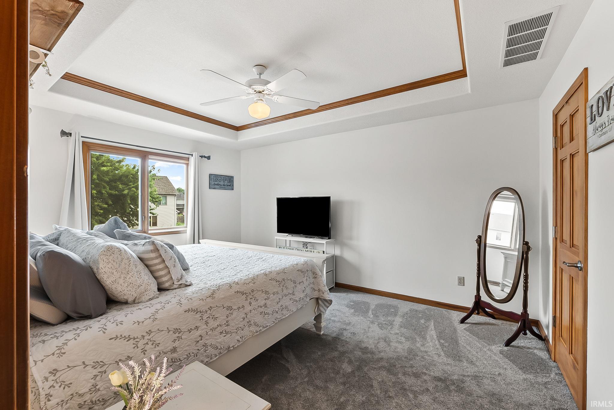 Recessed ceiling with wood trim, ceiling fan, and carpeted flooring