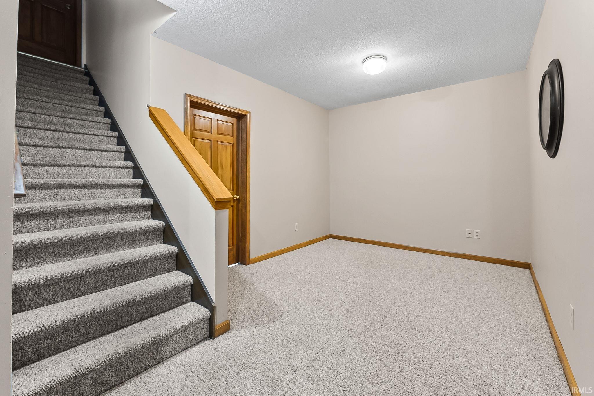 Carpeted staircase with a natural wood handrail