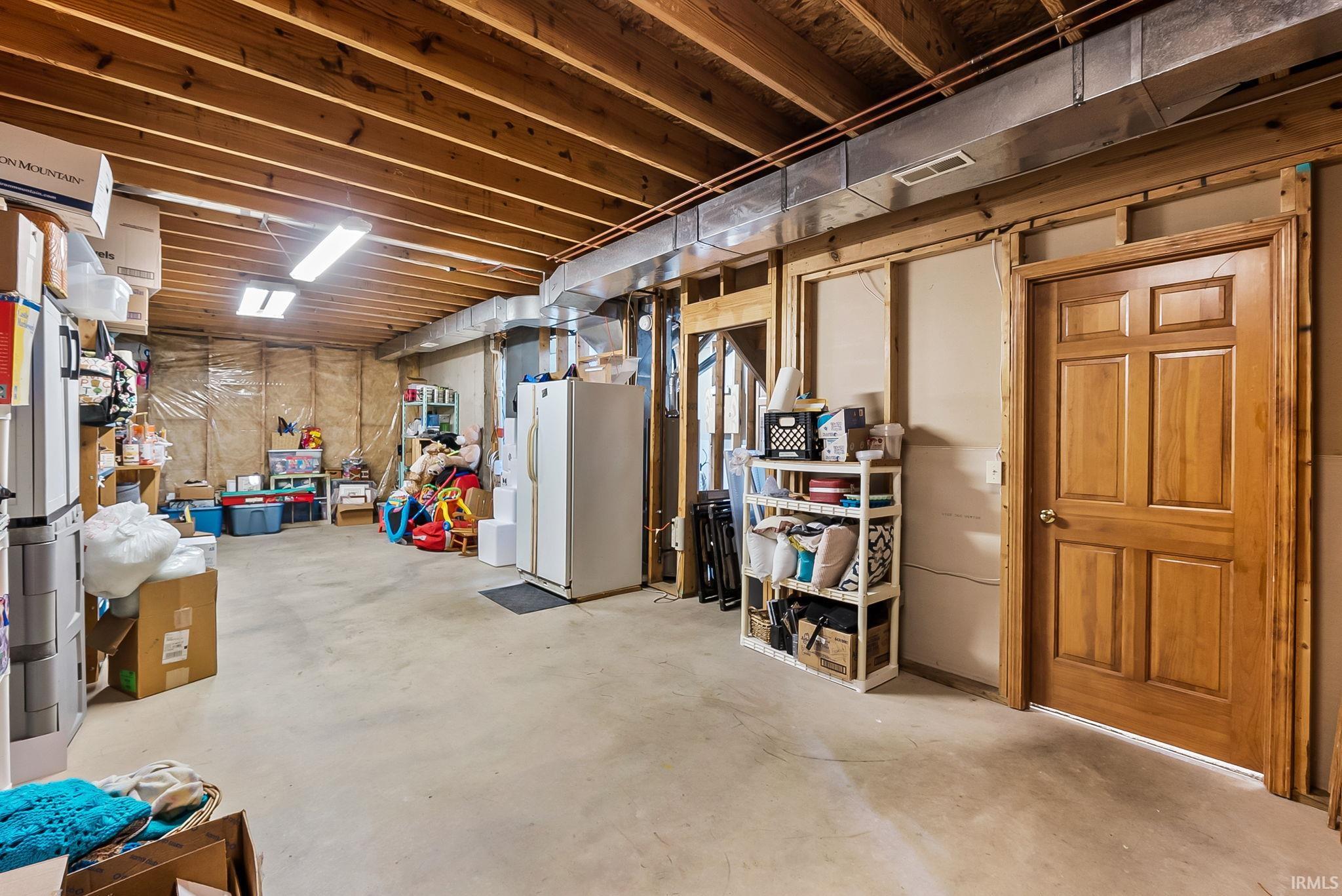 Unfinished basement featuring exposed wood ceiling joists and concrete flooring