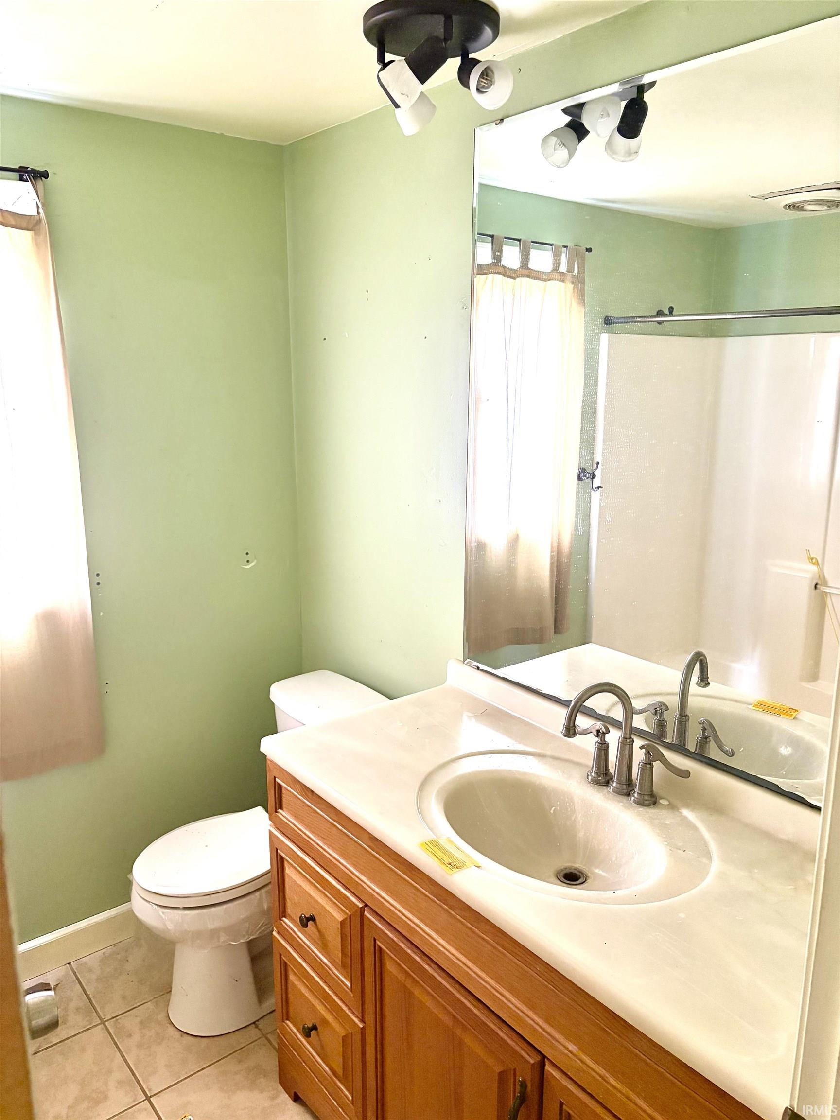 Bathroom vanity featuring a light wood-finish cabinet with multiple drawers and doors, a white integrated sink, and a light-toned countertop