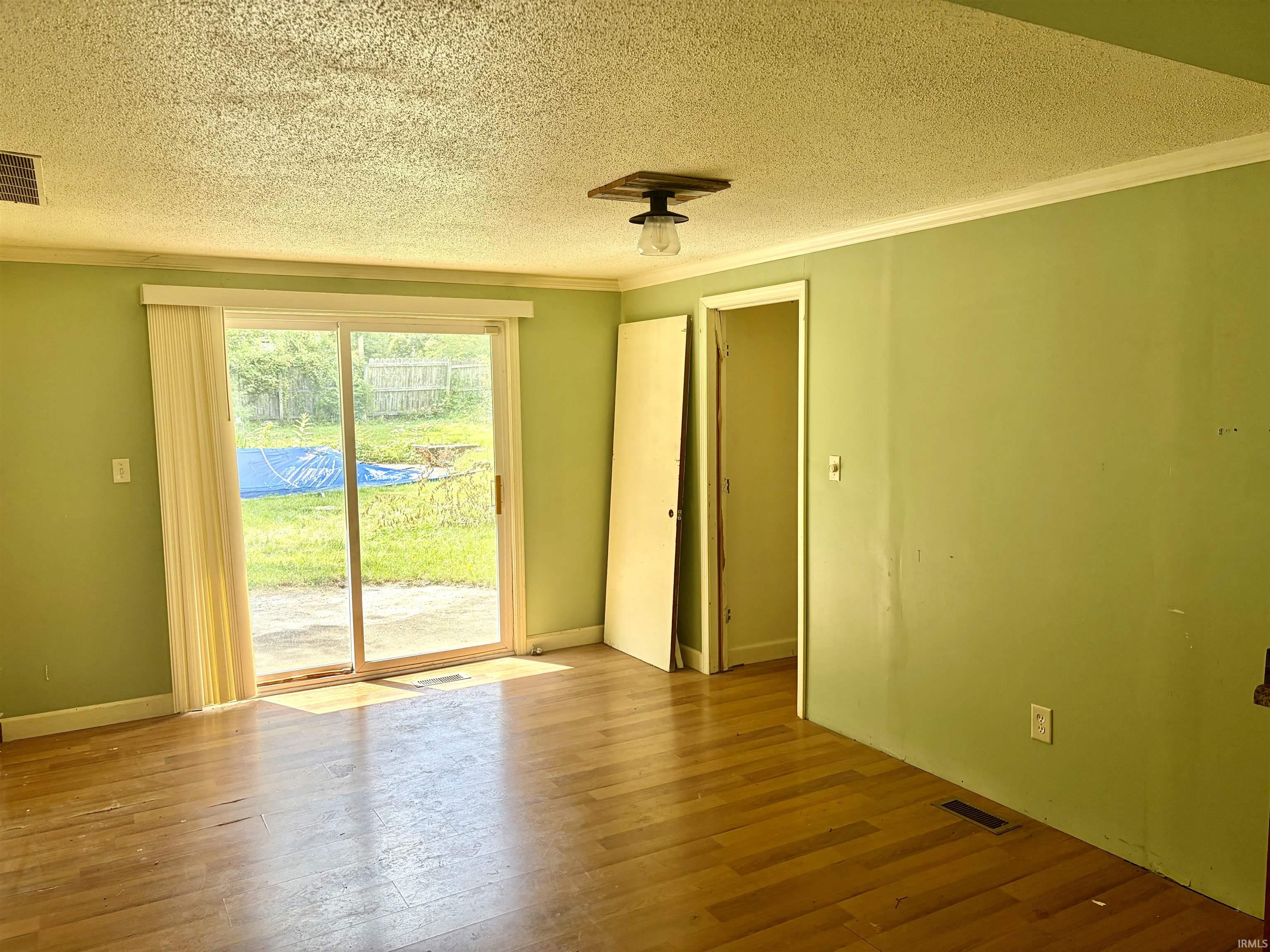 Hardwood-style flooring extends throughout this room, featuring light green walls and a white textured ceiling