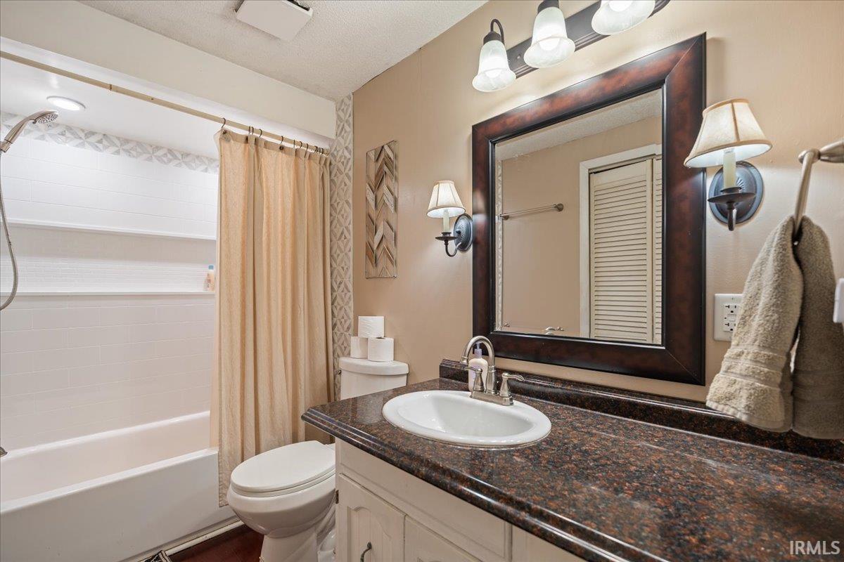 Bathroom featuring a white vanity with an integrated sink, a dark speckled countertop, and a framed mirror