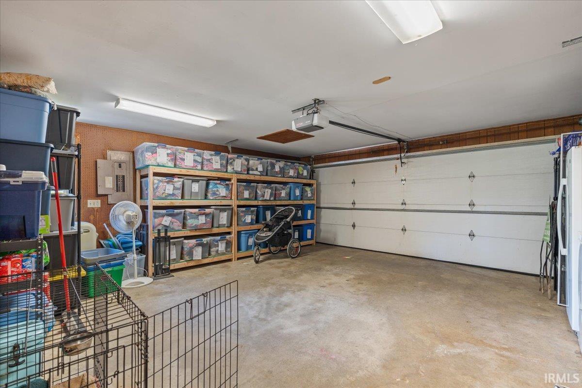 Spacious garage featuring a large automatic garage door, overhead lighting, and built-in shelving for organized storage