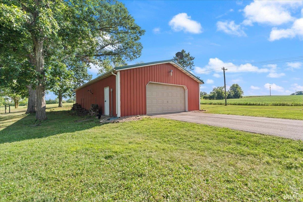 Red agricultural building with a light-colored garage door and a side entry door