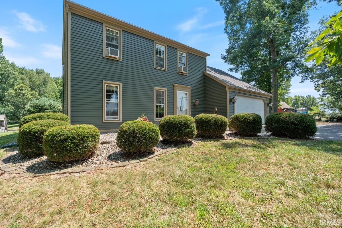 Two-story residence featuring deep green horizontal siding with cream trim around windows and doors