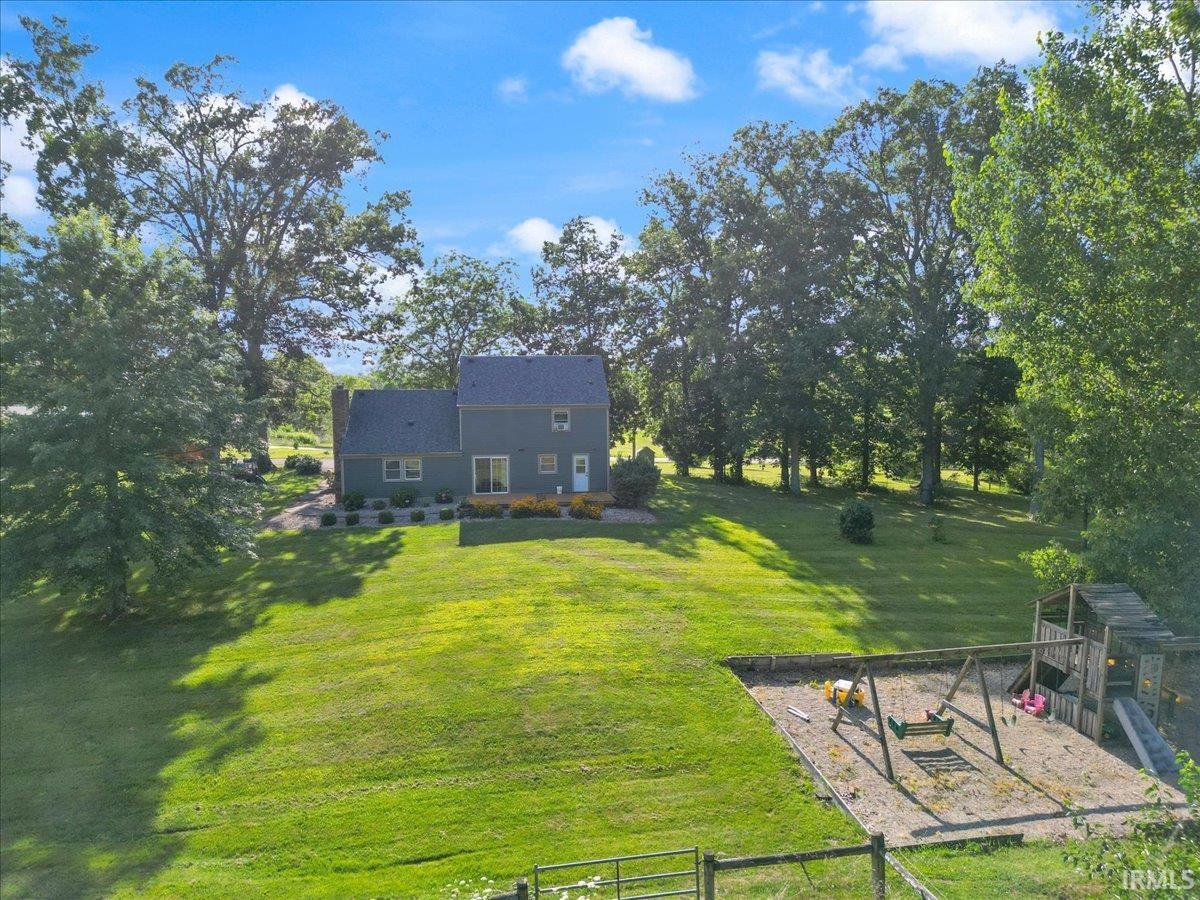 Expansive green lawn with mature trees and a dedicated playset area