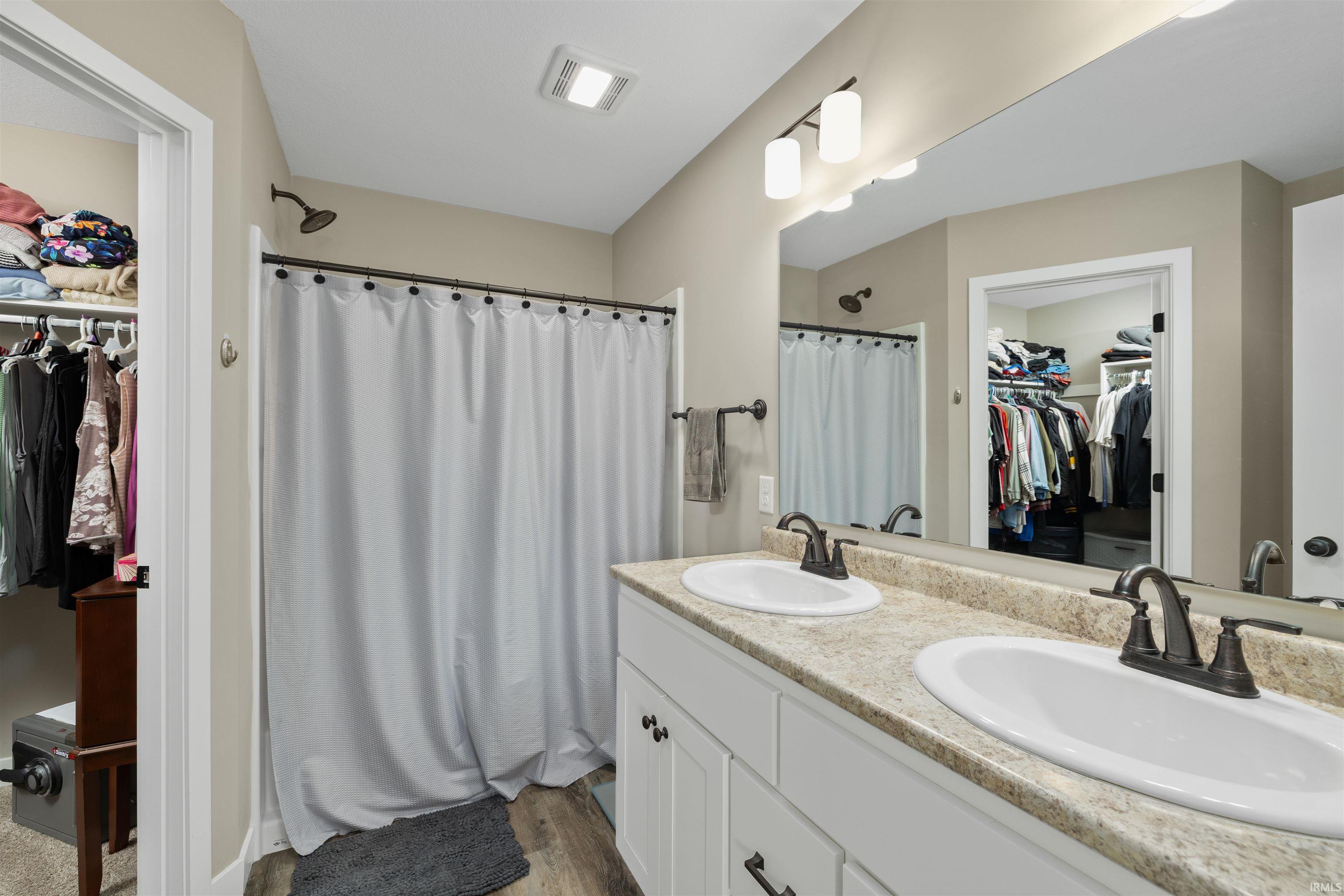 Bathroom featuring a dual vanity with light-toned countertops, white cabinetry, and bronzed fixtures