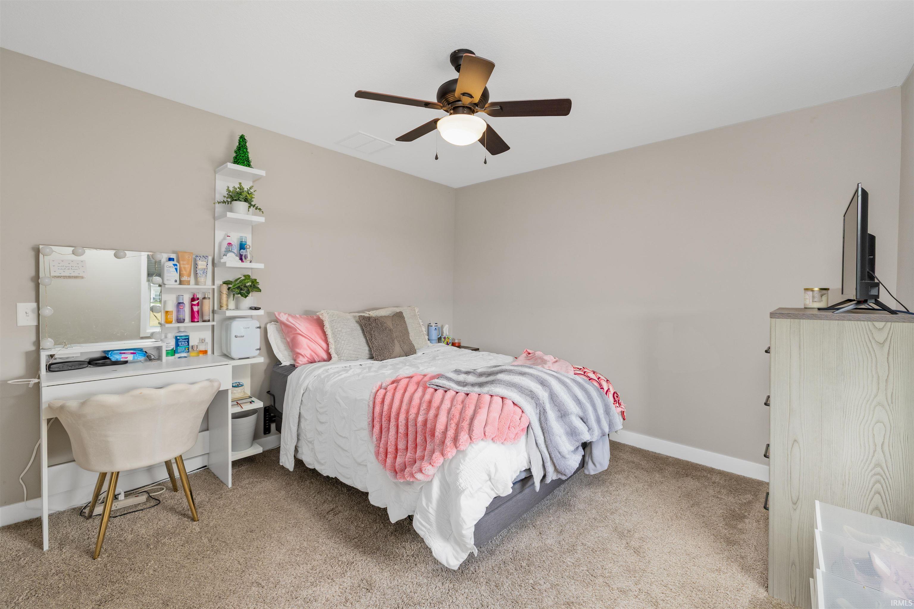 Bedroom featuring neutral wall colors, carpet flooring, a ceiling fan with integrated lighting, and a built-in wall shelf