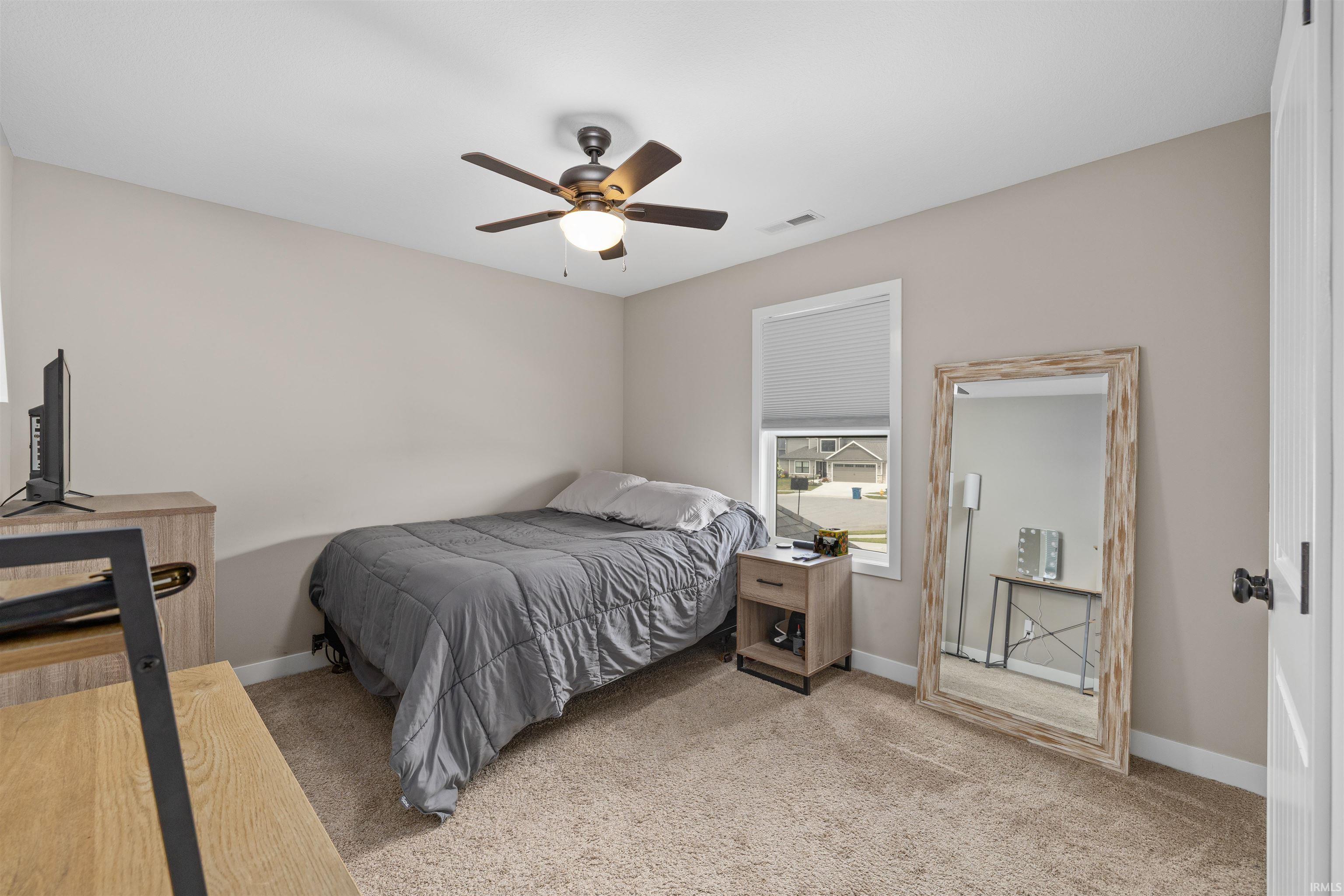 Carpeted room featuring a ceiling fan with integrated lighting, neutral wall tones, a window with blinds, and white trim