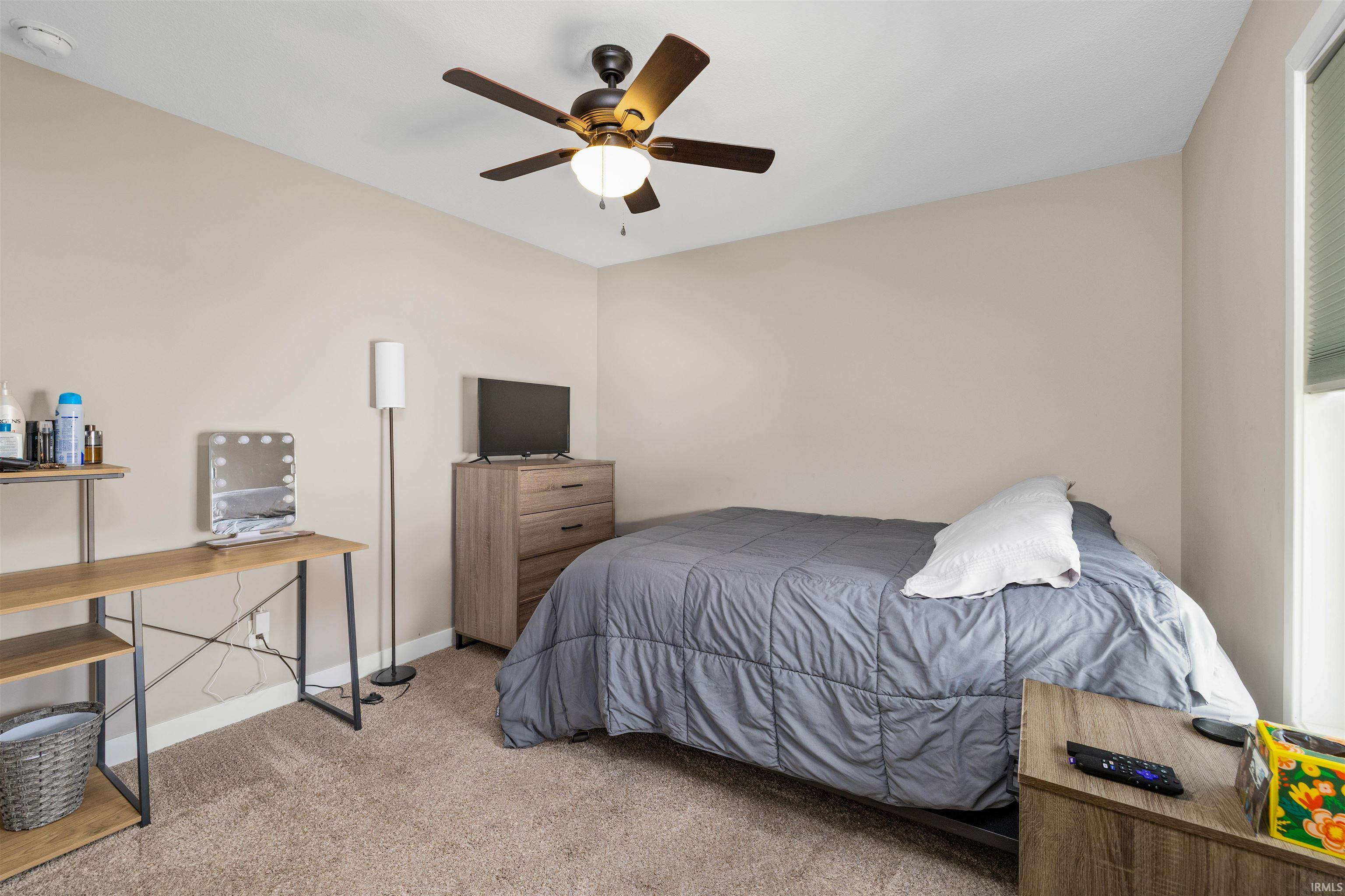 Carpeted room featuring a ceiling fan with integrated lighting, neutral wall paint, and a window with blinds