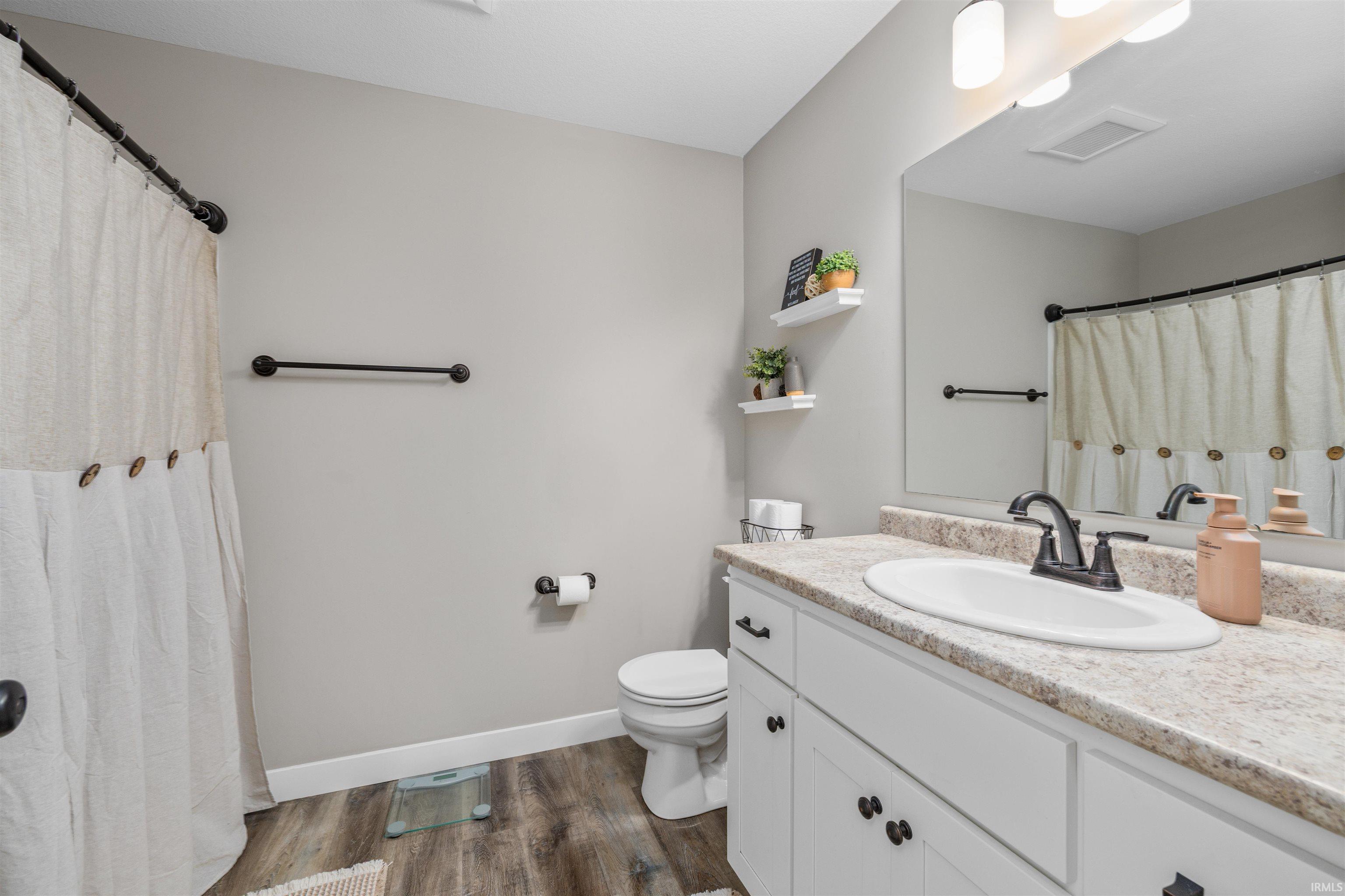 Bathroom featuring a single vanity with an integrated sink, dark hardware, and a light-toned countertop