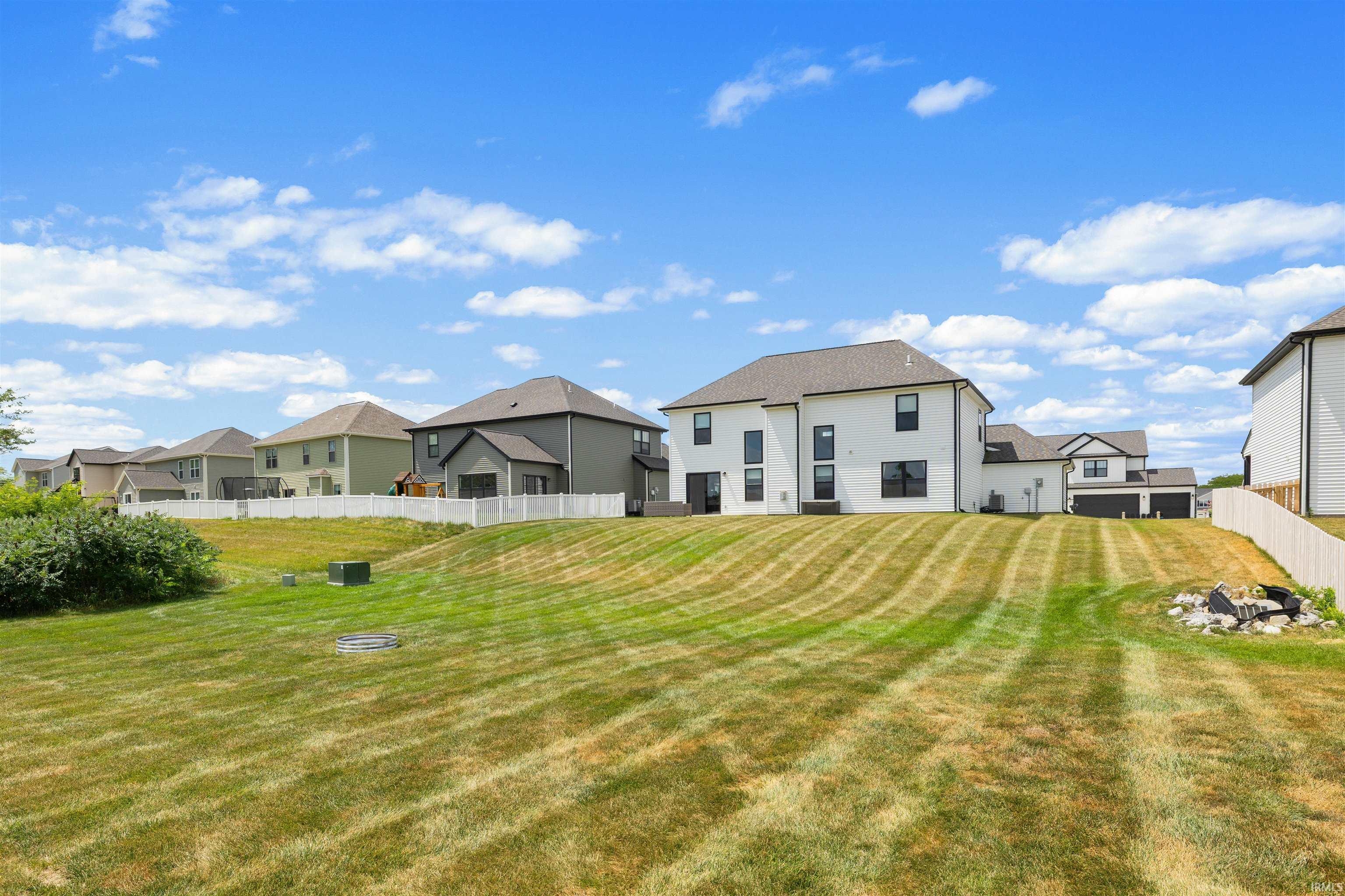 Spacious backyard with a sloped lawn and a white picket fence