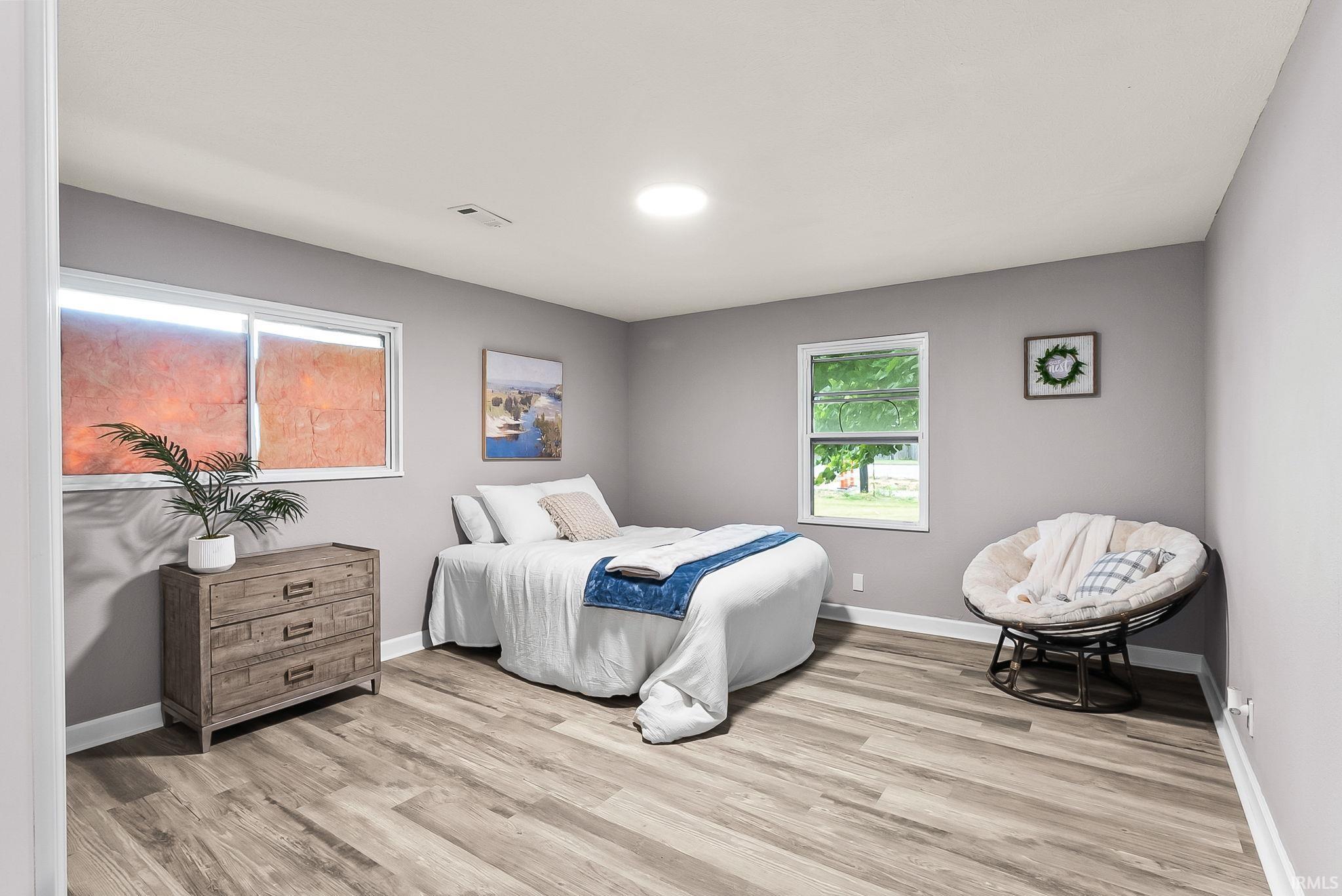 Spacious room featuring wood-finish flooring, light grey wall paint, white trim, and a ceiling-mounted light fixture