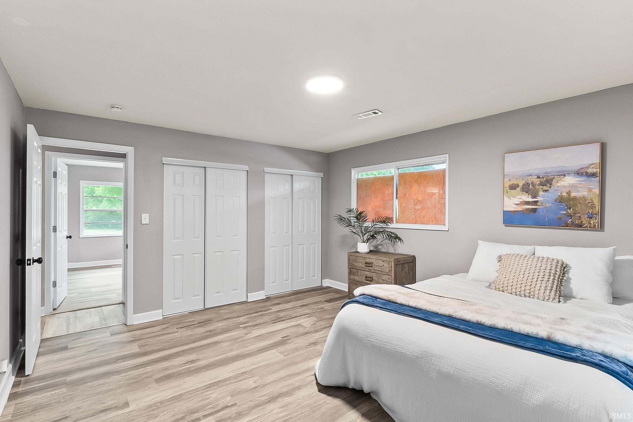 Spacious room featuring wood-finish flooring, two sets of white bifold closet doors, and recessed ceiling lighting