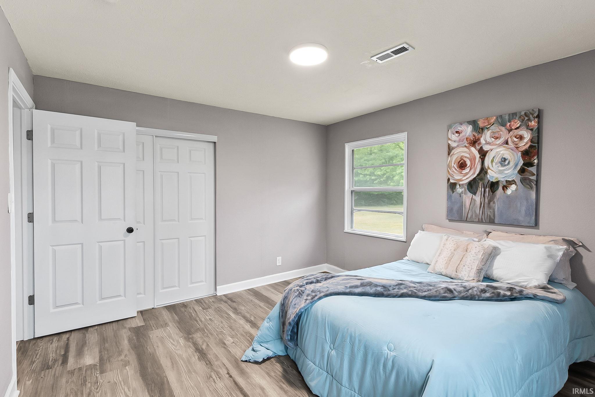 Bedroom with wood-finish flooring, two-panel interior doors, a single window, and a ceiling light fixture