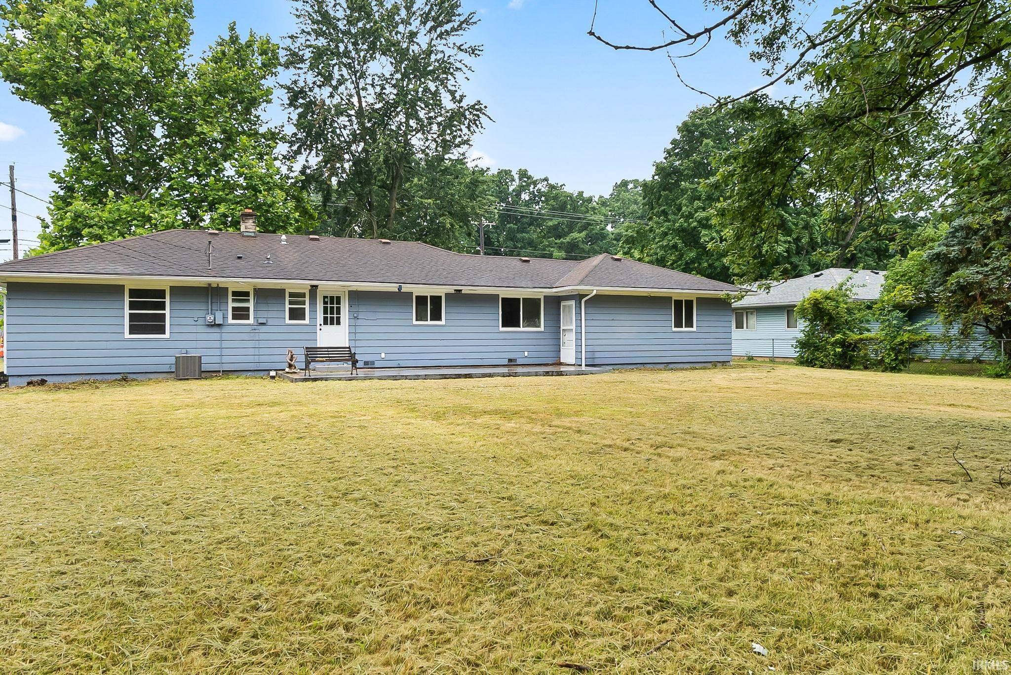 Expansive rear lawn with a light blue siding exterior and white trim windows